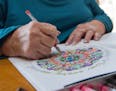 Beth Camasar colors an adult coloring book in her New London, Conn. home Thursday, Jan. 7, 2016. Camasar lost feeling in her hands a year ago and is t