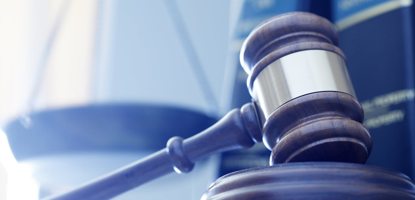 iStock
A gavel rests on its sounding block with a several law books and a justice scale out of focus in the background.