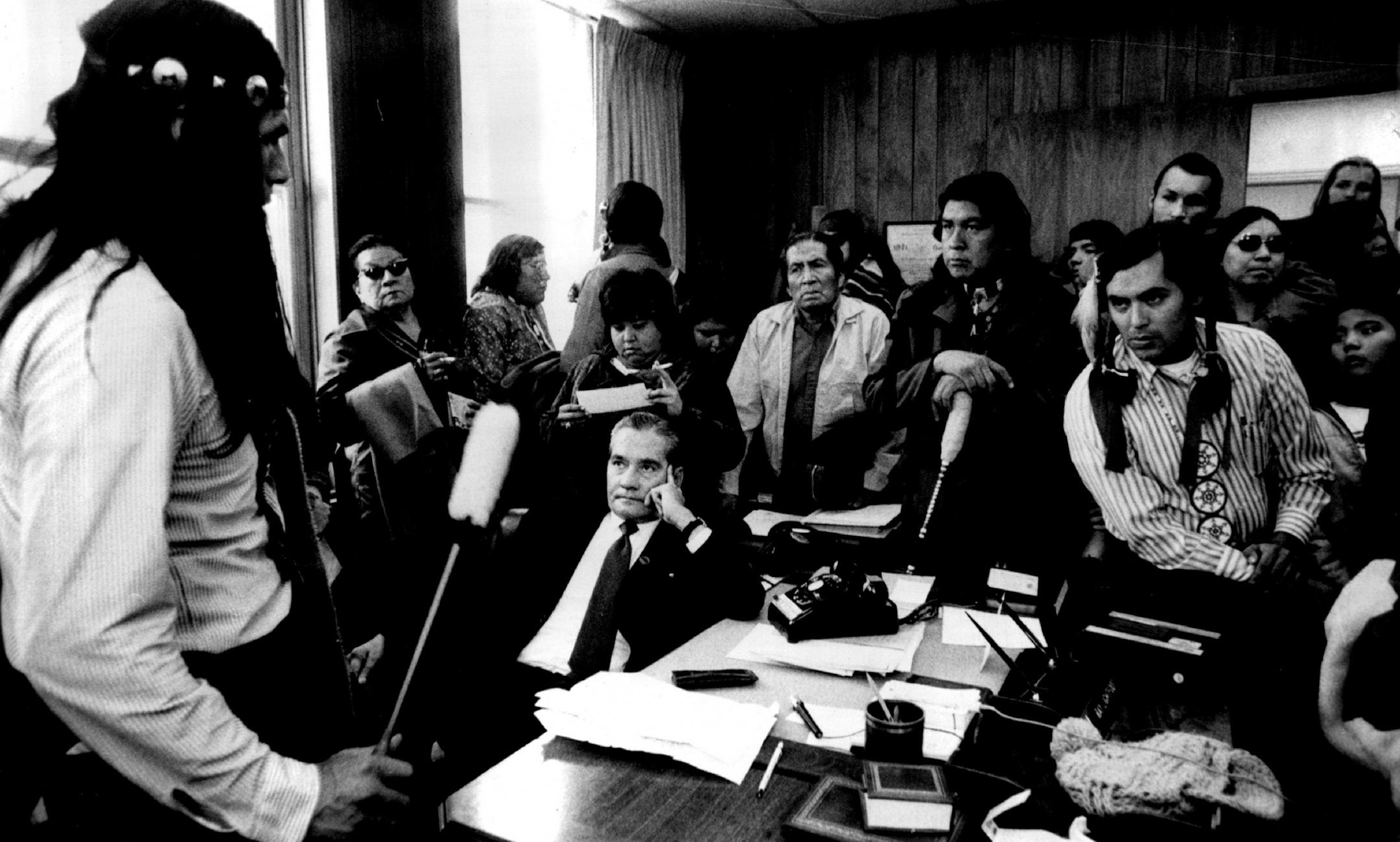 October 26, 1972: Dennis Banks, left, and about 75 Native Americans from 12 states surrounded Area BIA Director Ray Lightfoot, seated, in his Minneapolis office.