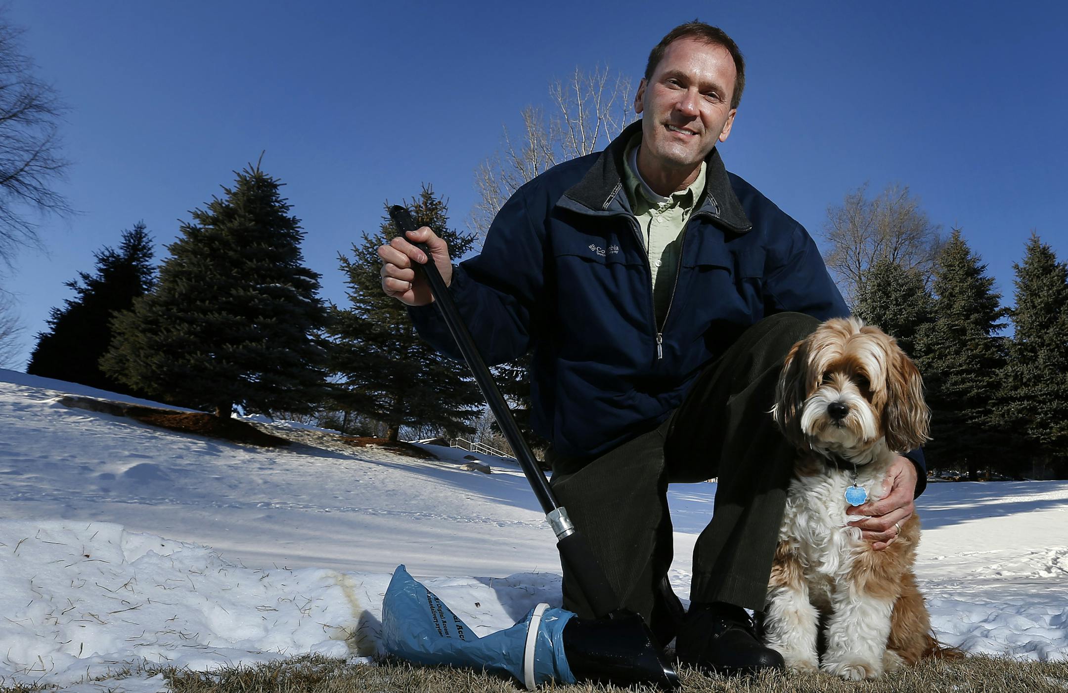 Tom Zurn posed with his family dog Wilson a Tibetan Terrier and his invention the PooBagger. ] CARLOS GONZALEZ cgonzalez@startribune.com, January 12, 2015, Eden Prairie, Minn., Tom Zurn, a graphic designer by profession, quit his day job two years after he designed and launched Minnesota made "PooBagger," a plastic tool that scoops up dog poop into a (recycled Star Tribune plastic bag) without having to bend over. He got the idea for what is a $39.99 product (sold online and at Bed Bath & Beyond