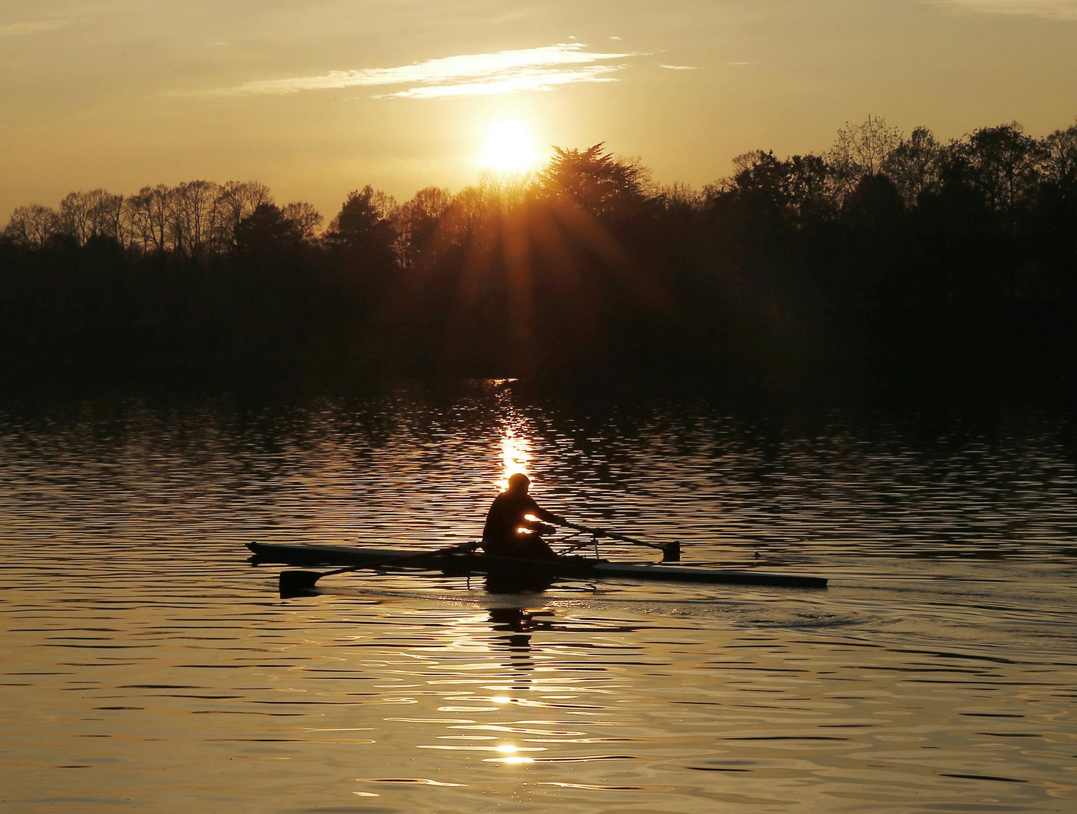 A man rows as he trains at sunset, at the Idroscalo artificial lake, in Milan, Italy, Thursday, Nov. 26, 2015. (AP Photo/Antonio Calanni)