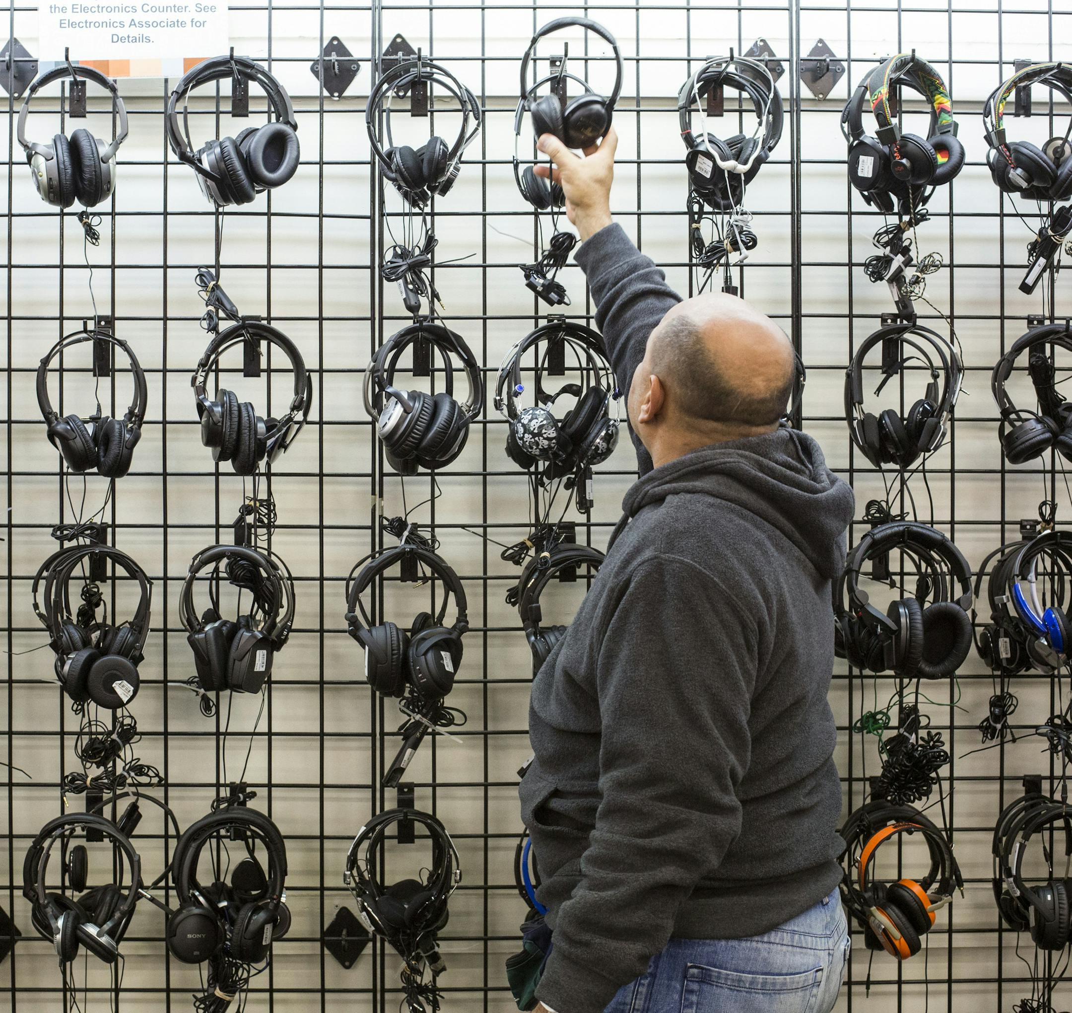 A shopper looks at a wall of headphones at the Unclaimed Baggage Center in Scottsboro, Ala., Nov. 19, 2014. While the number of checked ìmishandledî luggage items is declining, the boon in carry-on belongings left in seat-back compartments and overhead bins ó think iPads ó has helped keep this repository of orphaned property thriving. (Joe Buglewicz/The New York Times) ORG XMIT: XNYT116
