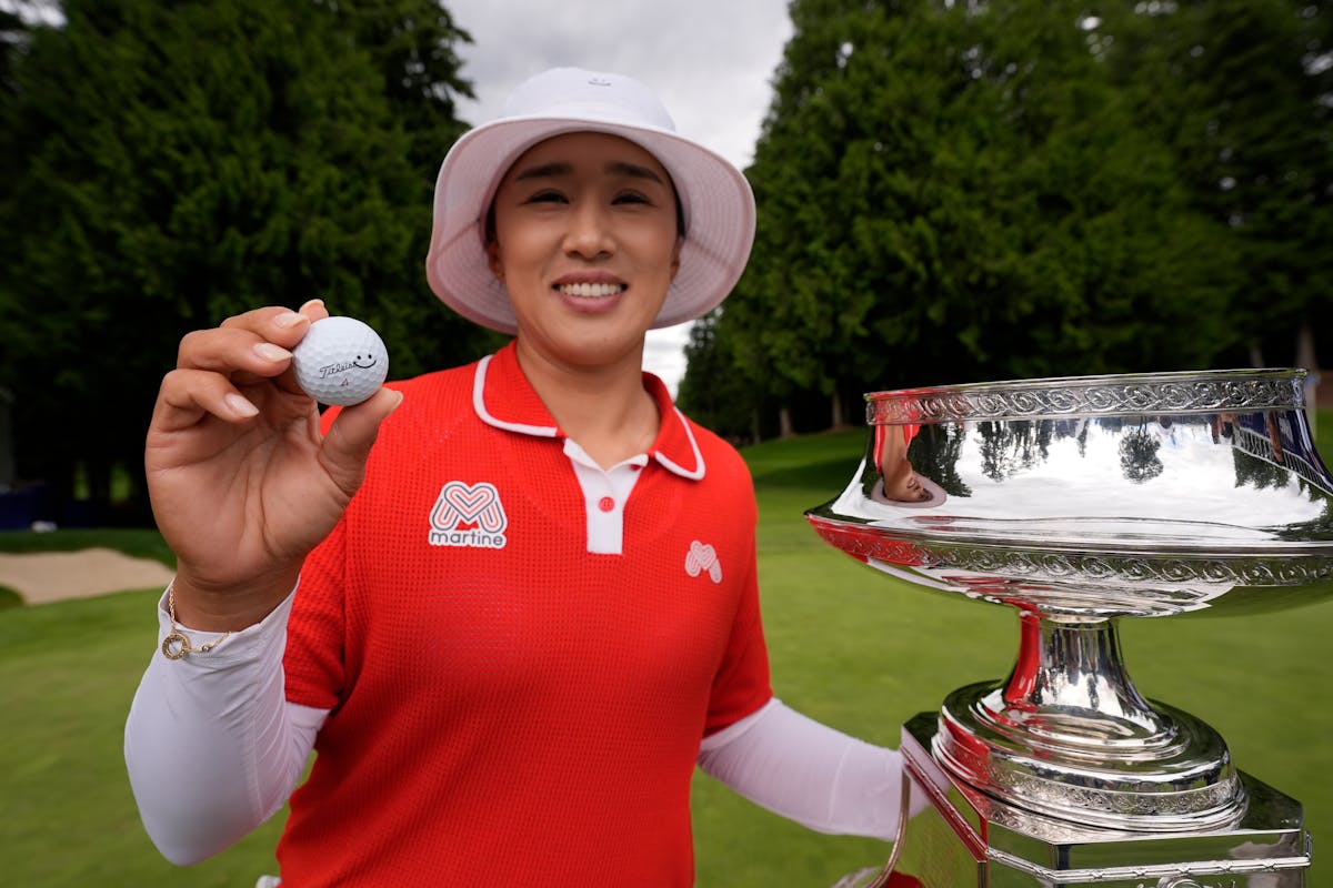 Amy Yang of South Korea displays her golf ball with a smiley face on it as she poses next to the trophy after winning the Women's PGA Championship on 