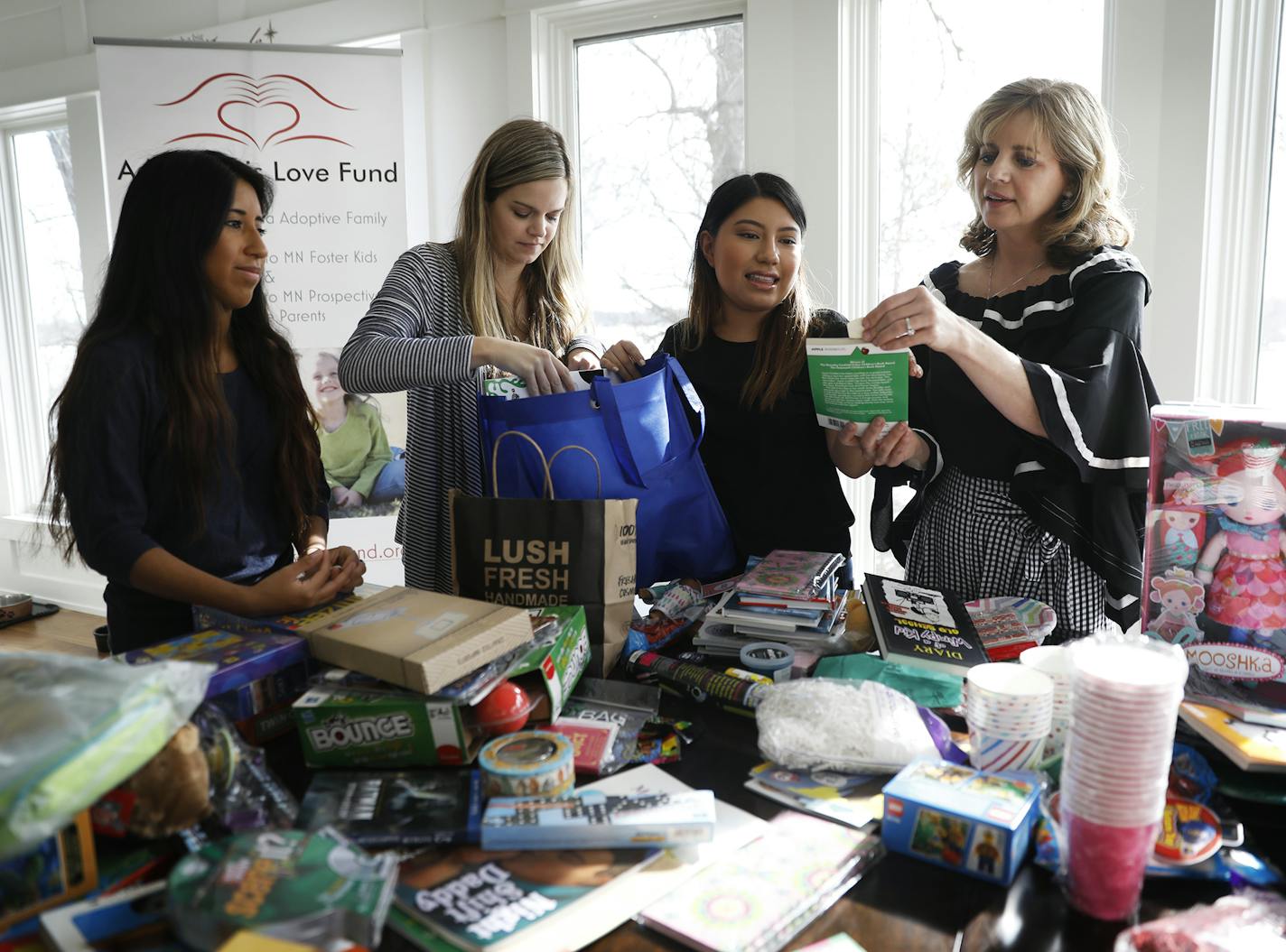 Julie Ledy, from right, founder of the nonprofit "Adoption is Love" puts together birthday bags for foster kids with her daughters Jillian Ledy, 20, Jenna Huiras, 29, and Chloe Ledy, 17. ] LEILA NAVIDI &#xef; leila.navidi@startribune.com BACKGROUND INFORMATION: Julie Ledy, founder of the nonprofit "Adoption is Love" puts together birthday bags for foster kids with her daughters in her Roseville home on Friday, March 23, 2018.