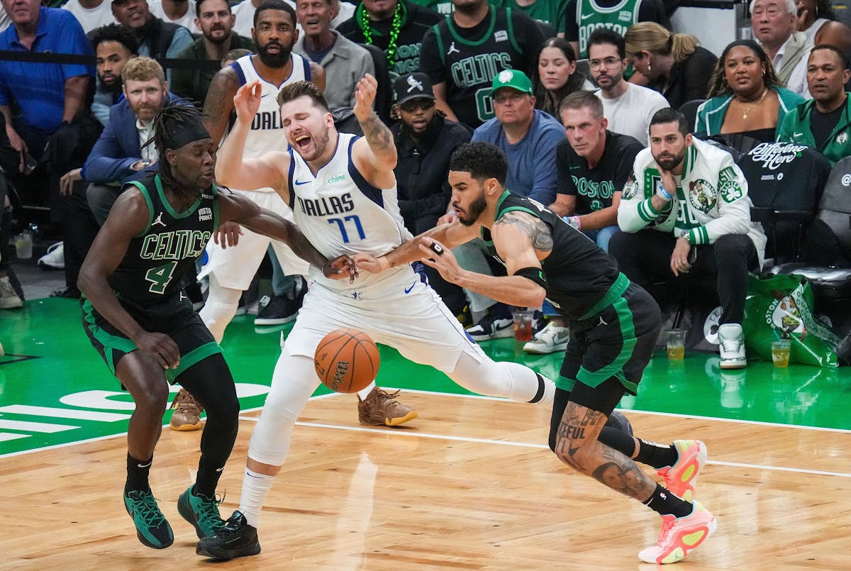 Dallas Mavericks guard Luka Doncic loses the ball as Boston Celtics guard Jrue Holiday, left, and forward Jayson Tatum defend during the first half in