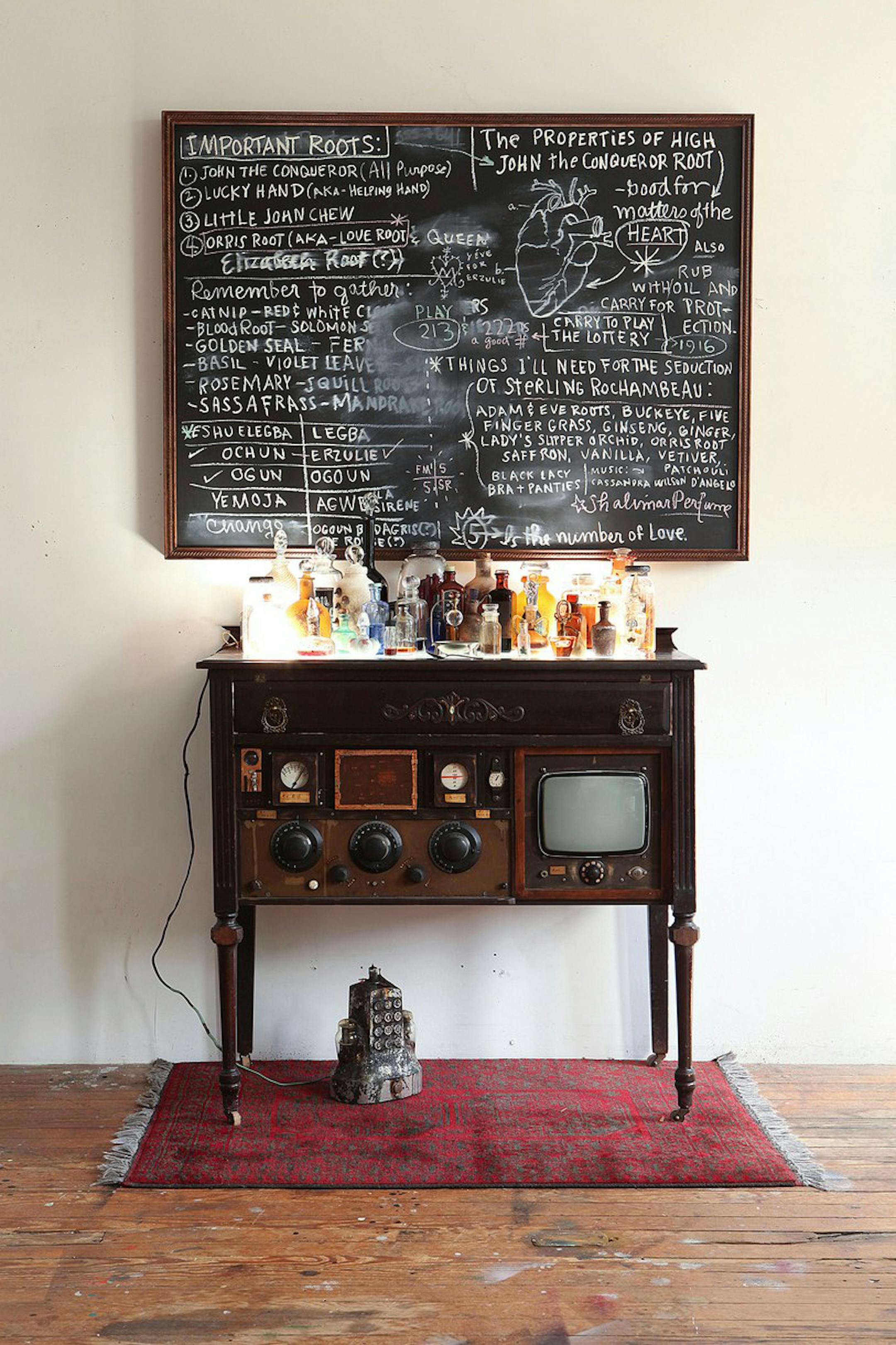 Renée Stout. American, born 1958. The Rootworker's Worktable, 2011. Altered and reconstructed table, blown and hot-formed glass, found and constructed objects, oil stick on panel, found carpet, 78 x 50 x 30 in. Karen and Robert Duncan Collection, Lincoln NE. Photo: Renée Stout.