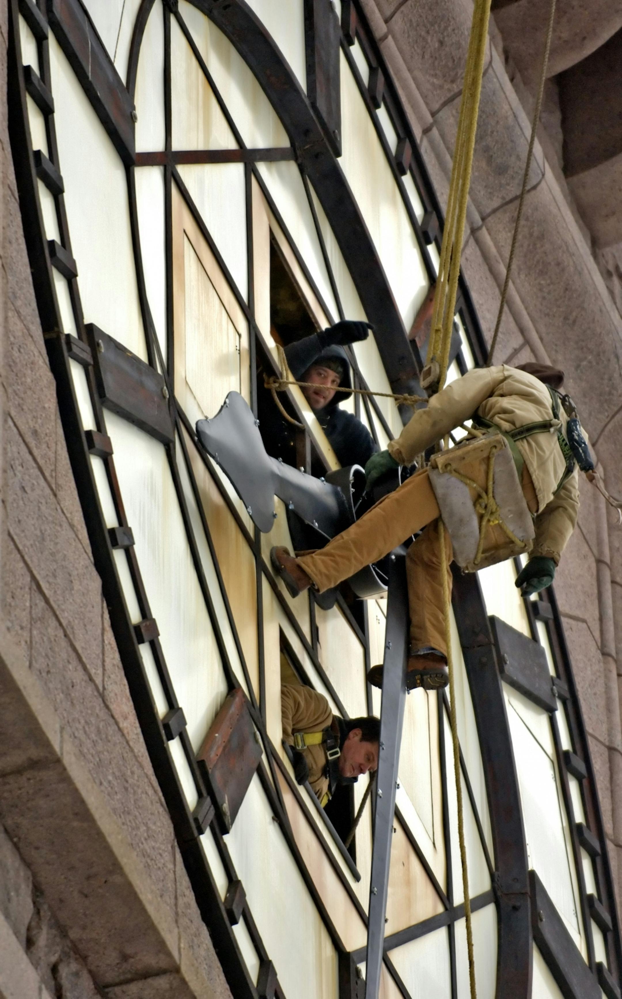 CITY HALL CLOCK TOWER RESTORATION Workers moved the referbished clock hands into position on the Minneapolis City Hall clock tower's south face Thursday afternoon. On the outside of the clock face was steeple jack Keith Goyette, with Krause Konstruction in Stoddard,Wisconsin, and assisting him from the inside were John Witkowiak (below), the owner of Lee Manufacturing, and Scott Helm (above) also from Lee Manufacturing. The clips that will hold the lighted neon tubing can just be seen on the clo