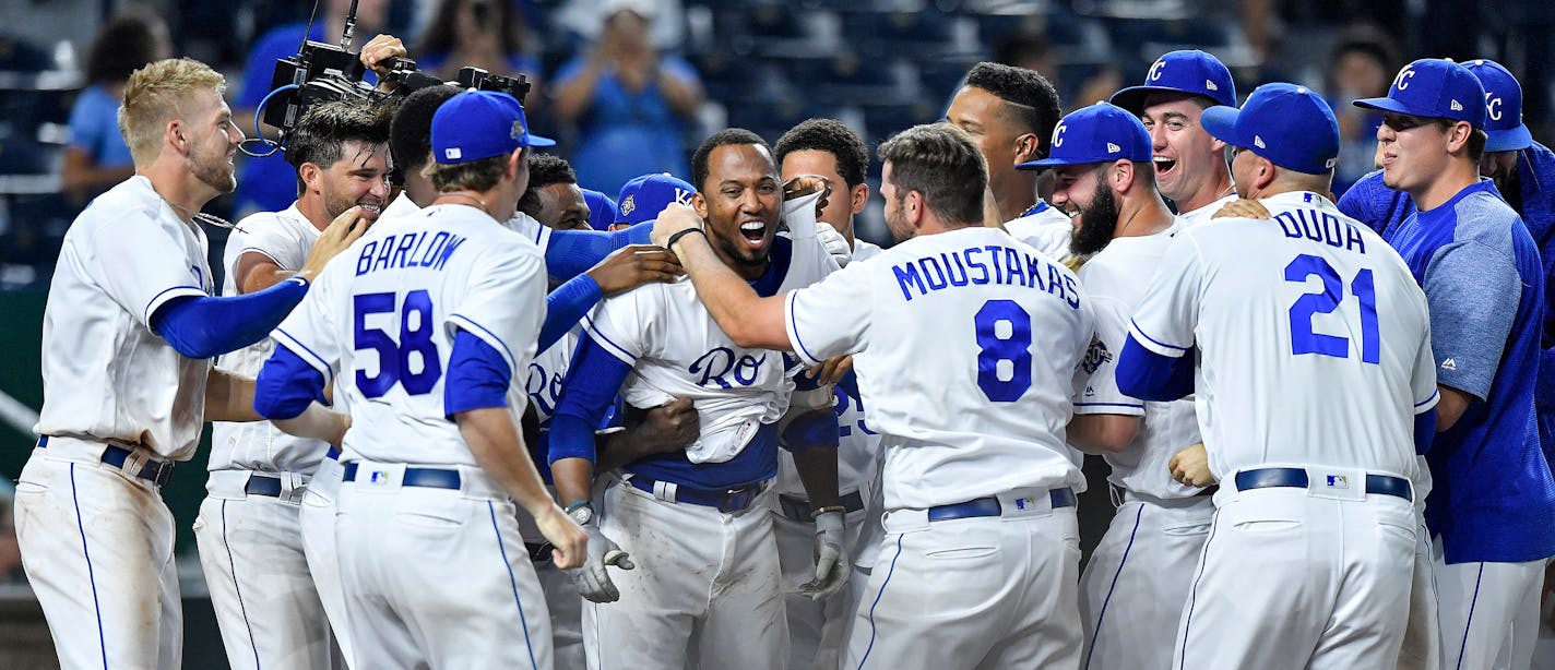 The Kansas City Royals' Alcides Escobar is surrounded by teammates after hitting the game-winning home run in the 14th inning against the Twins