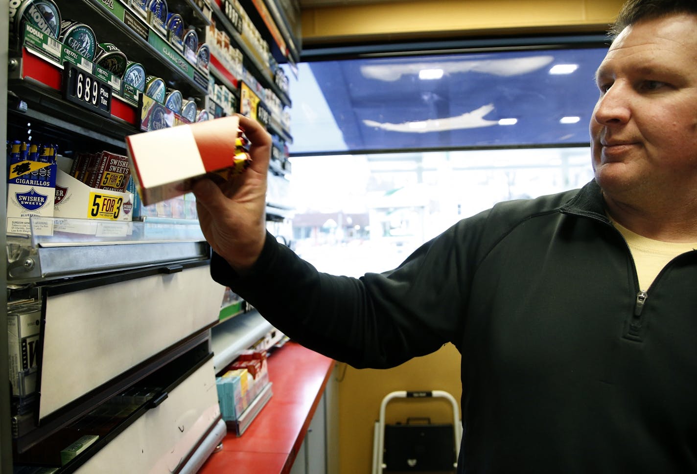 Brian Henderson owner of the Highland Park BP station in St. Paul replaced a box of cigarillos. A proposed St. Paul law raising the tobacco purchasing age would penalize retailers for selling to customers under 21, but not the customers.