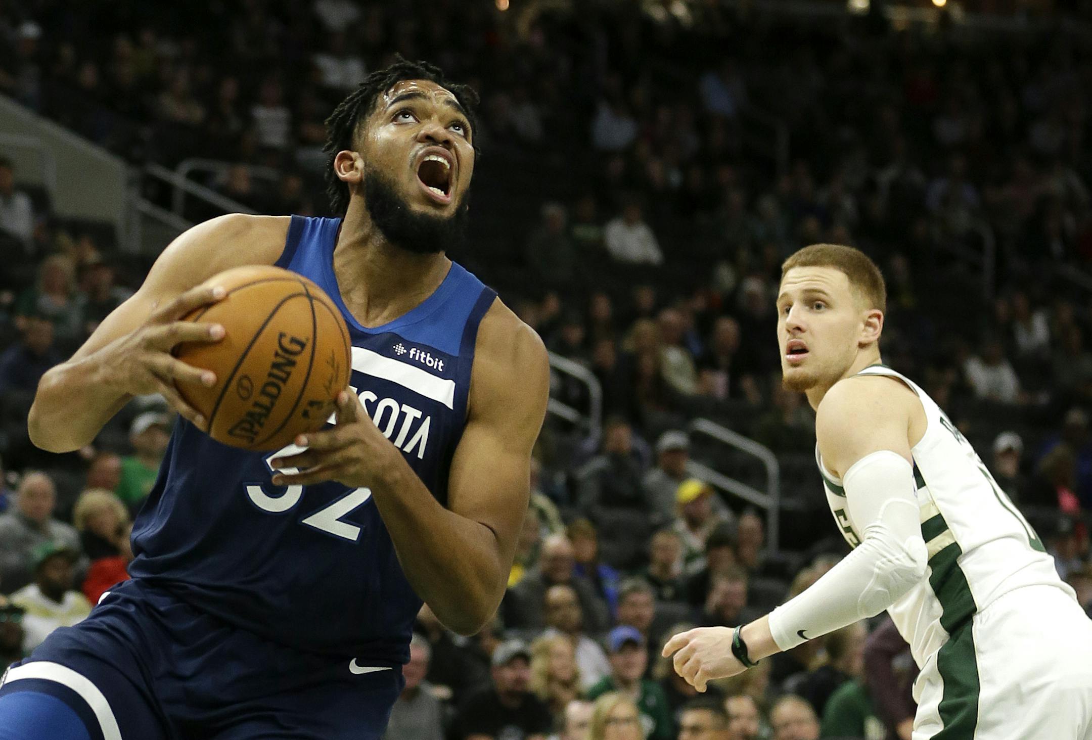 Minnesota Timberwolves' Karl-Anthony Towns, left, drives past Milwaukee Bucks' Donte DiVincenzo during the second half of a preseason NBA basketball game Thursday, Oct. 17, 2019, in Milwaukee. (AP Photo/Aaron Gash)