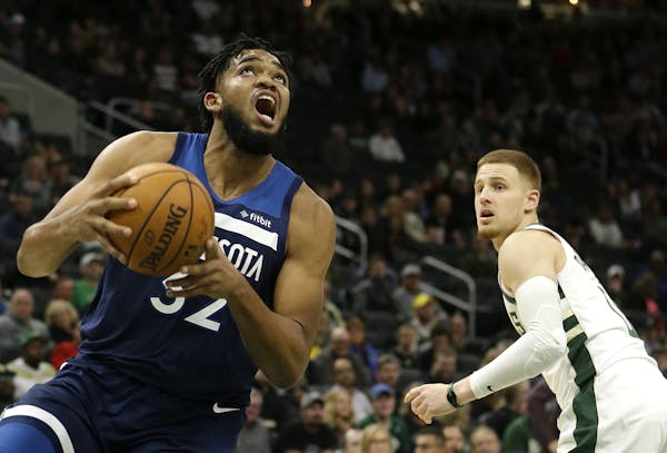 Minnesota Timberwolves' Karl-Anthony Towns, left, drives past Milwaukee Bucks' Donte DiVincenzo during the second half of a preseason NBA basketball g