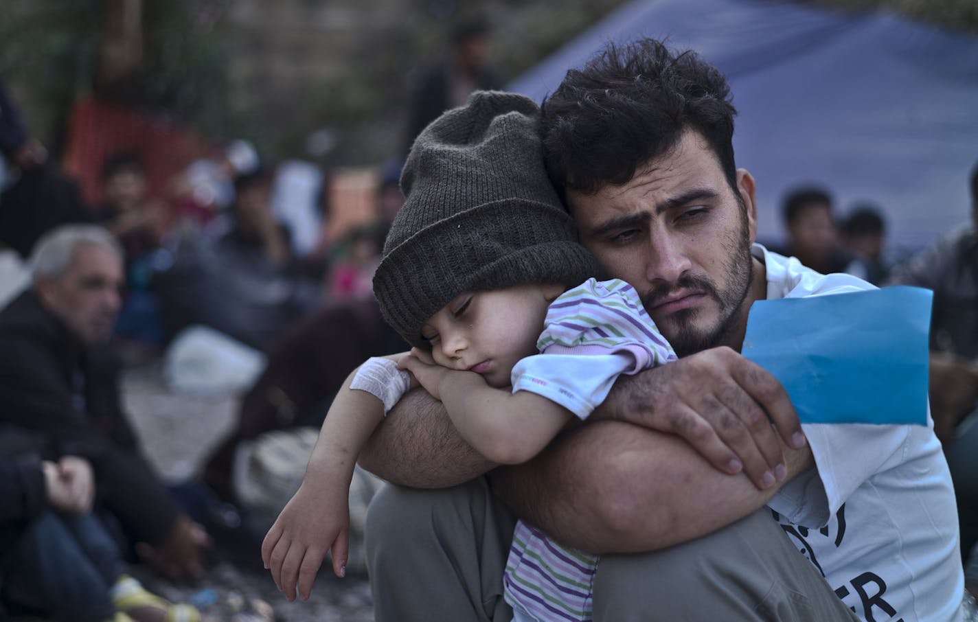 FILE - In this Sunday, Oct. 4, 2015 file photo, a Syrian refugee child sleeps in his father's arms while waiting at a resting point to board a bus, after arriving on a dinghy from the Turkish coast to the northeastern Greek island of Lesbos. Bold ideas for helping Syrian refugees and their overburdened Middle Eastern host countries are gaining traction among international donors who were shocked into action by this year's migration of hundreds of thousands of desperate Syrians to Europe. (AP Pho