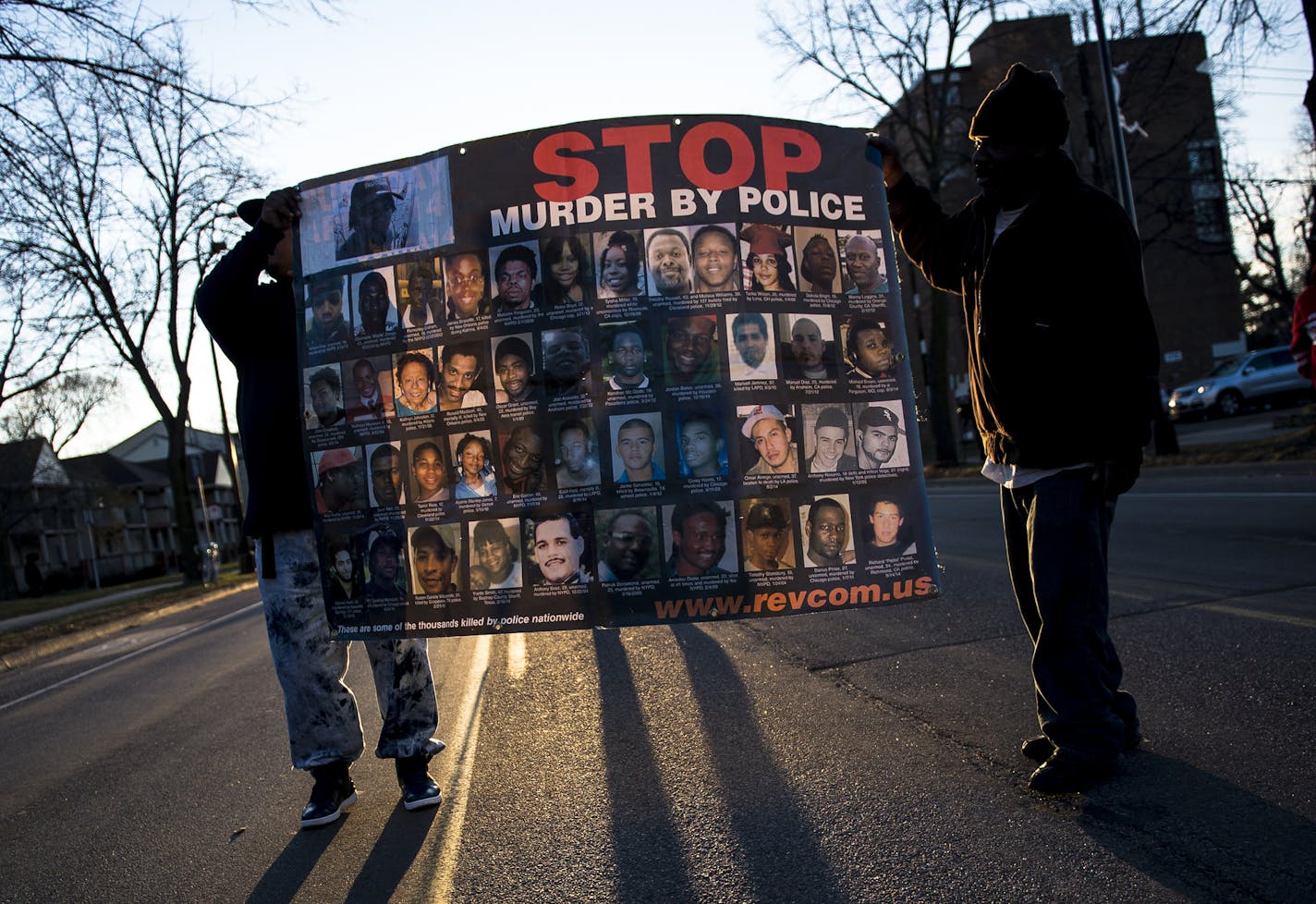 Demonstrators held a sign with the faces and names of men, women and children killed by police during a vigil at the Jamar Clark memorial in north Minneapolis on Friday.