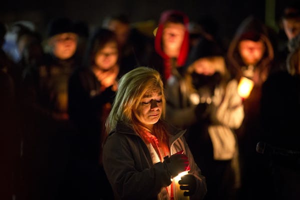 Rachel Brady, sister of Nick Brady, 17, and cousin of Haile Kifer, 18, shielded a candle during Sunday evening's vigil in Little Falls.