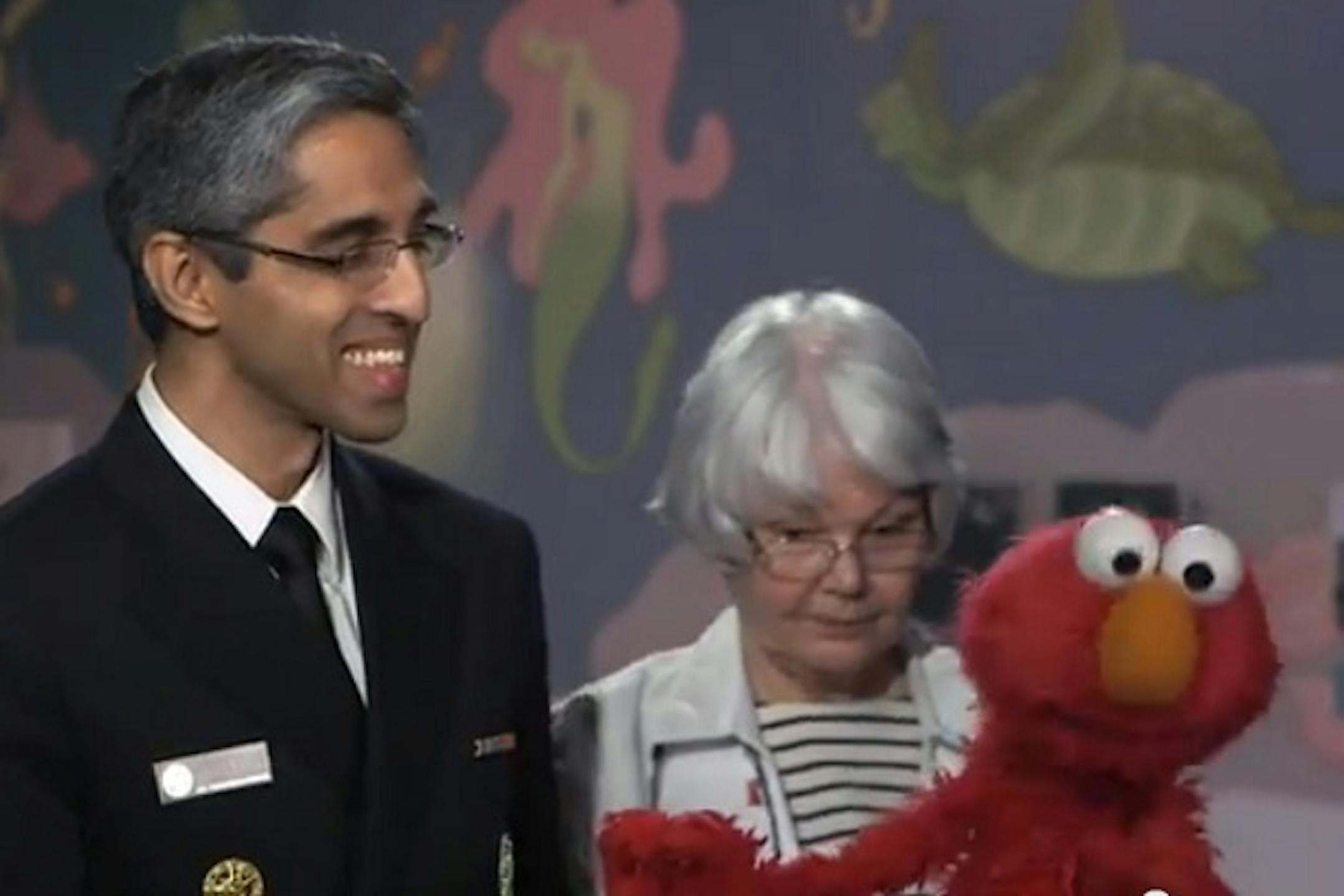 In the video, Elmo, at the doctor's office and nervous about receiving a shot, is greeted by U.S. surgeon general Vivek Murthy, who explains the importance of vaccinations.