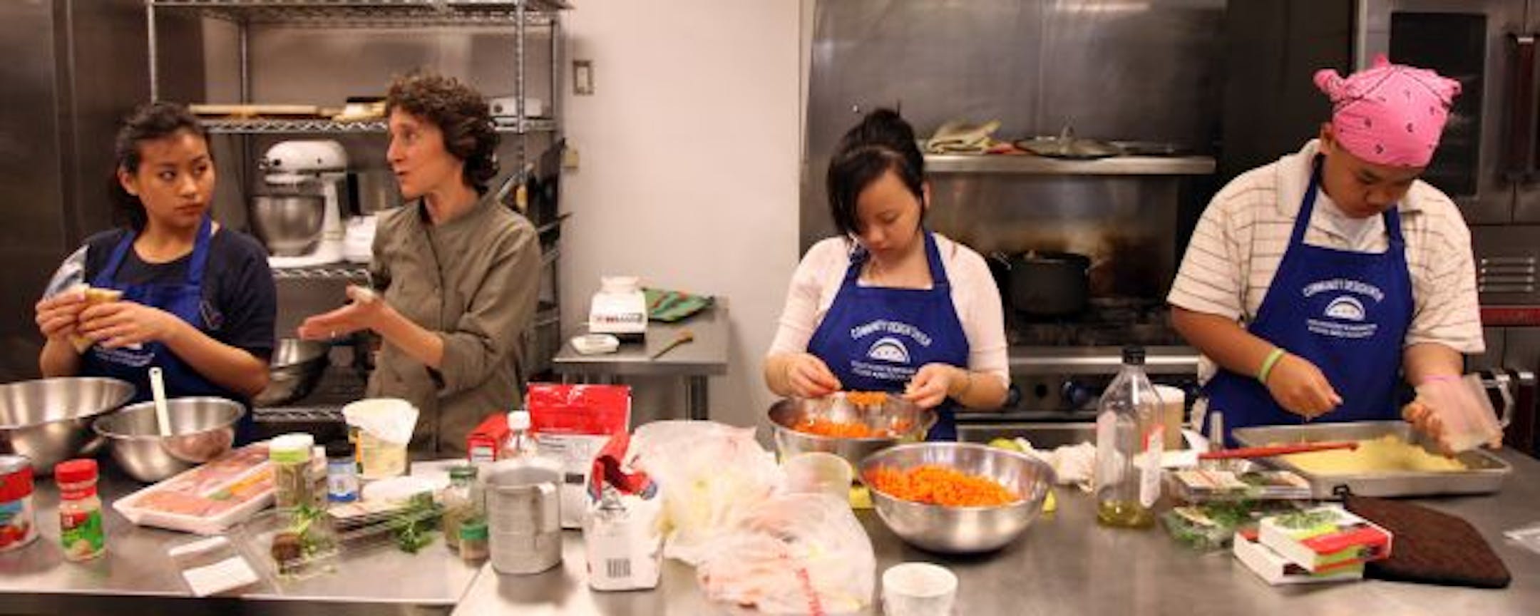 From left, students (in aprons) Vinnis Lee, Xia Lee and Kou Lee worked with chef Jenny Breen (second from left) in her kitchen at the Midtown Global Market to perfect recipes for the National Farm to Cafeteria Conference in Detroit. Their mission: to improve school lunches.