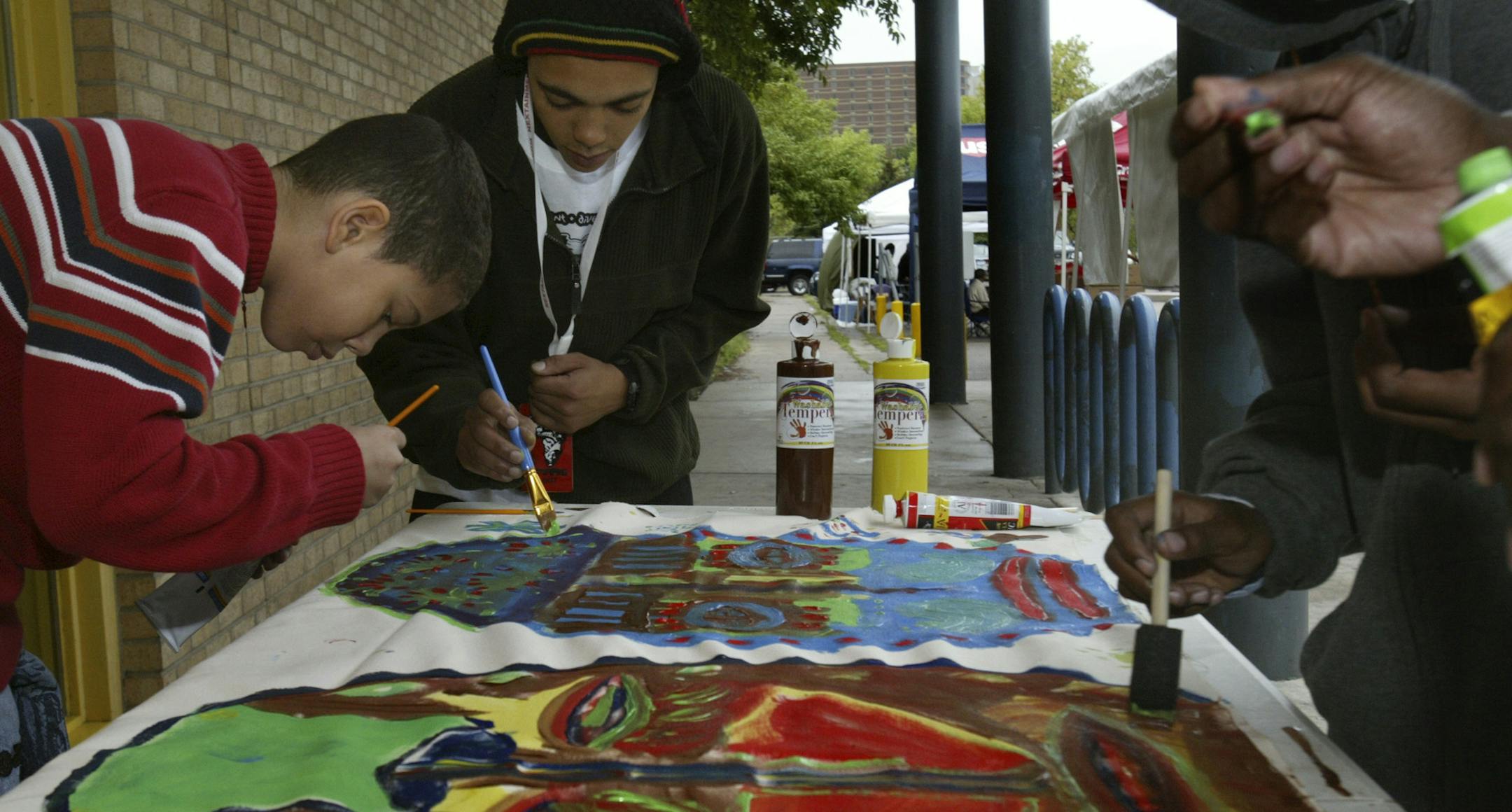 joel koyama•jkoyama@startribune.com
metro0820 112696 The 'Afrifest' event. From left to right-Garriuus Farr (red),Thabiso Rowan (middle) and Amin Amos (Grey), work on the Afriest Community Mural, a canvas 20 feet X 31/2 feet which was sketched out by artist Richard Amos and painted by the children and people of the community. The Mural will be donated to the Brian Coyle Community Center when it is completed.