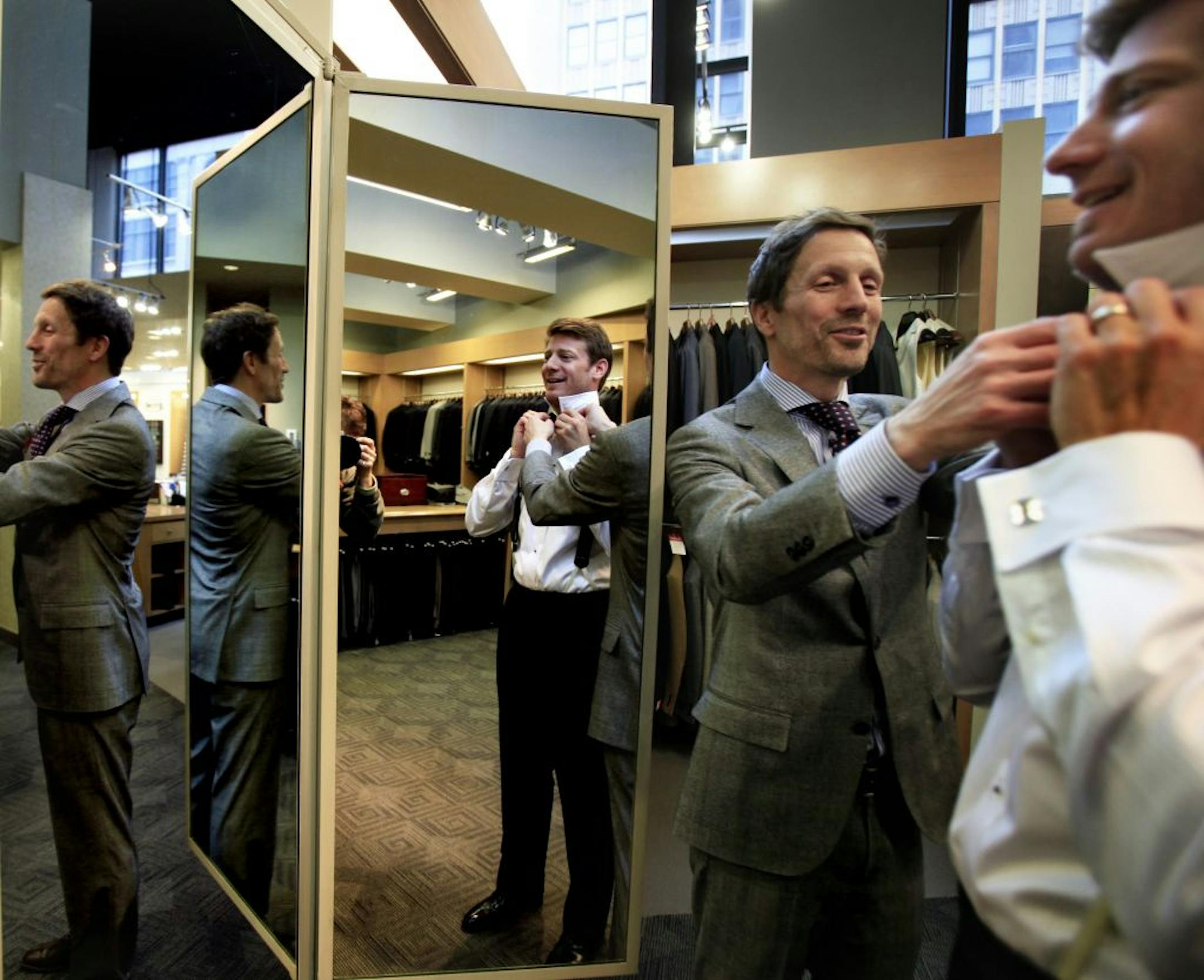 Chuck Simpkins (grey suit) at Hubert White men's store, shows his customer Jon Armour, a lawyer for the law firm Winthrop and Weinstine, how to tie a bowtie. Simpkins has worked 27 years in sales.