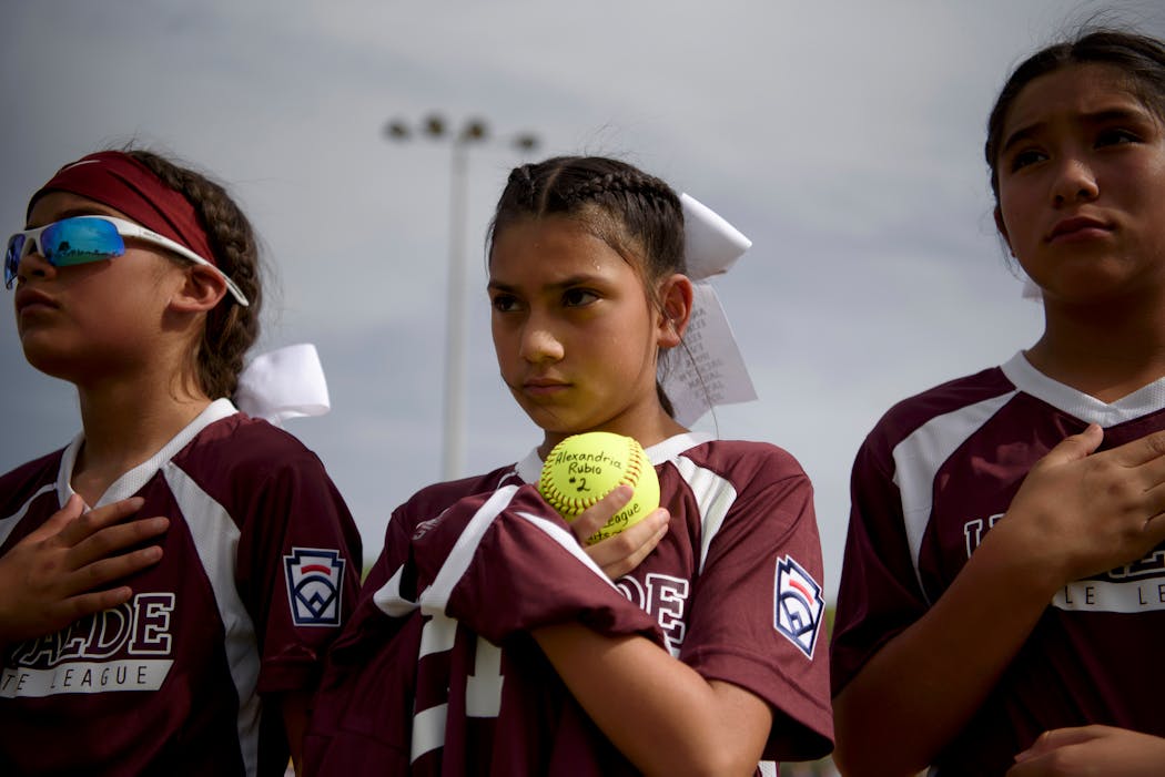 A player holds a softball bearing the name of Alexandria Rubio, one of the victims of the Robb Elementary School shooting.