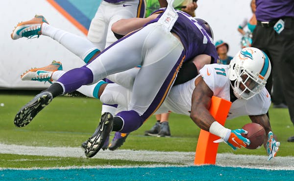Miami Dolphins' Mike Wallace wraps around an endzone pylon with the ball to score a third quarter touchdown as Minnesota Vikings' Harrison Smith fails
