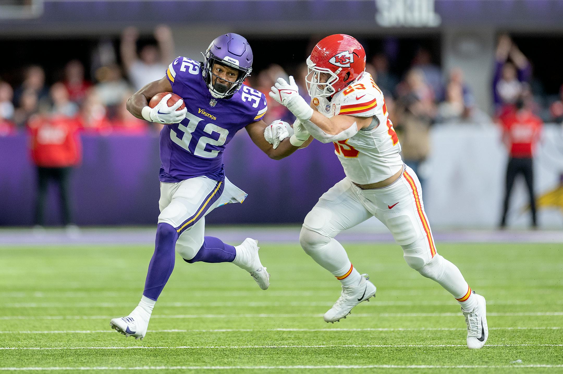 Vikings running back Ty Chandler (32) carries the ball for a first down defended by Chiefs linebacker Drue Tranquill (23) in a fake punt in the second quarter.