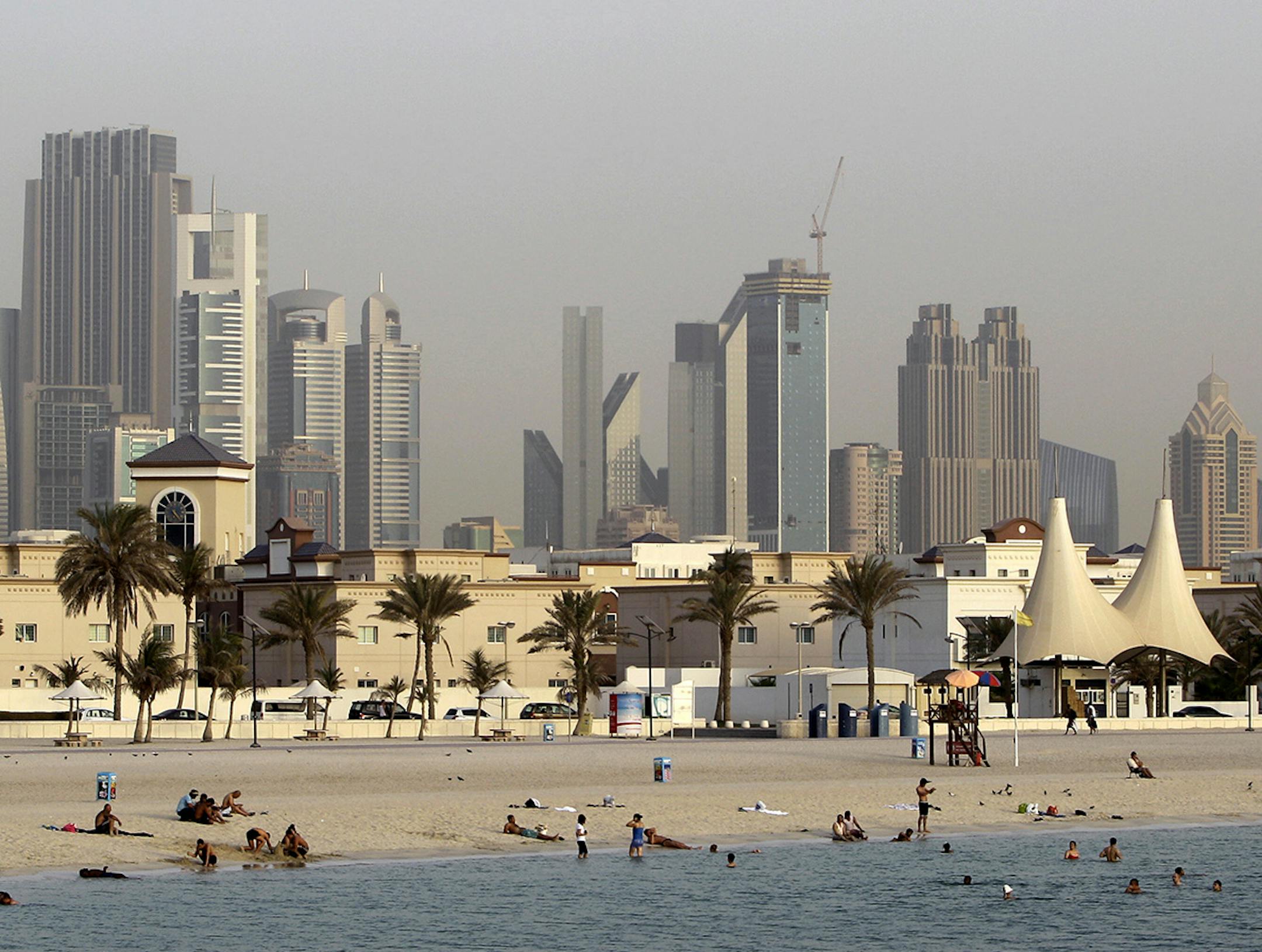 In this photo dated Thursday, July 26, 2012, people enjoy swimming at Jumeirah open beach with the city skyline in background, Dubai, United Arab Emirates. Not all Dubai beaches are hidden behind high-end hotels and waterfront palaces. Jumeirah Open Beach is one of the city's most popular, drawing everyone from Russian tourists and Arab families to Indian and Pakistani migrant workers relaxing on their day off. One you've had your fill of the white sand beach and sparkling Gulf waters, turn arou