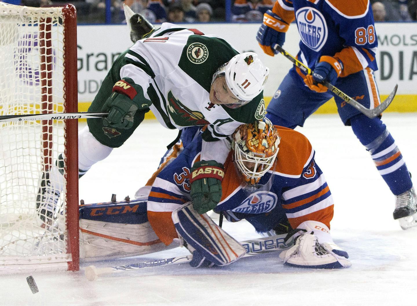 Minnesota Wild ' Zach Parise (11) crashes against Edmonton Oilers goalie Cam Talbot (33) as he dives for the puck during the first period of an NHL hockey game Thursday, Feb. 18, 2016, in Edmonton, Alberta. (Jason Franson/The Canadian Press via AP)