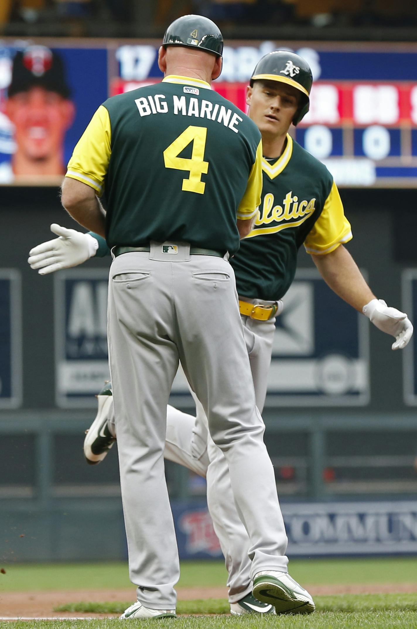 Oakland Athletics' Matt Chapman, right, is congratulated by third base coach Matt Williams,shown wearing his nickname, "Big Marine" on his jersey, following Chapman's solo home run off Minnesota Twins pitcher Jose Berrios in the first inning of a baseball game Sunday, Aug. 26, 2018, in Minneapolis. (AP Photo/Jim Mone)