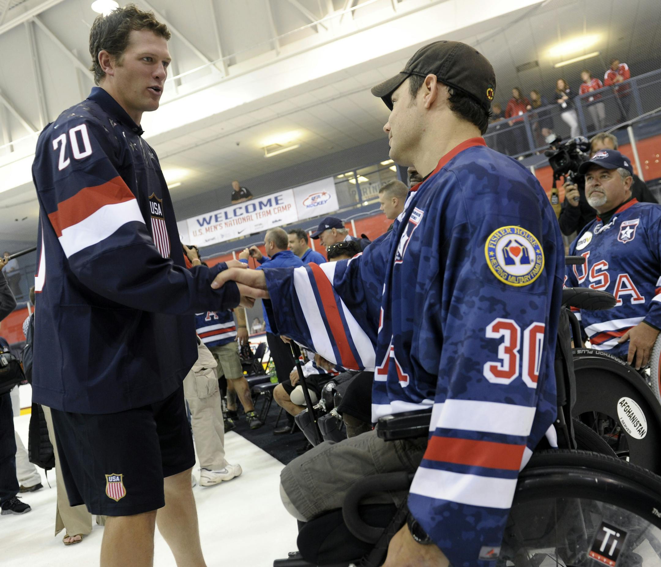 Ryan Suter, left, a member of the 2013 USA Hockey Men's National Team and a member of the NHL Minnesota Wild, shakes hands with a member of the USA Warriors Ice Hockey team during an event at the Kettler Captials Iceplex in Arlington, Va., Tuesday, Aug. 27, 2013. (AP Photo/Susan Walsh)