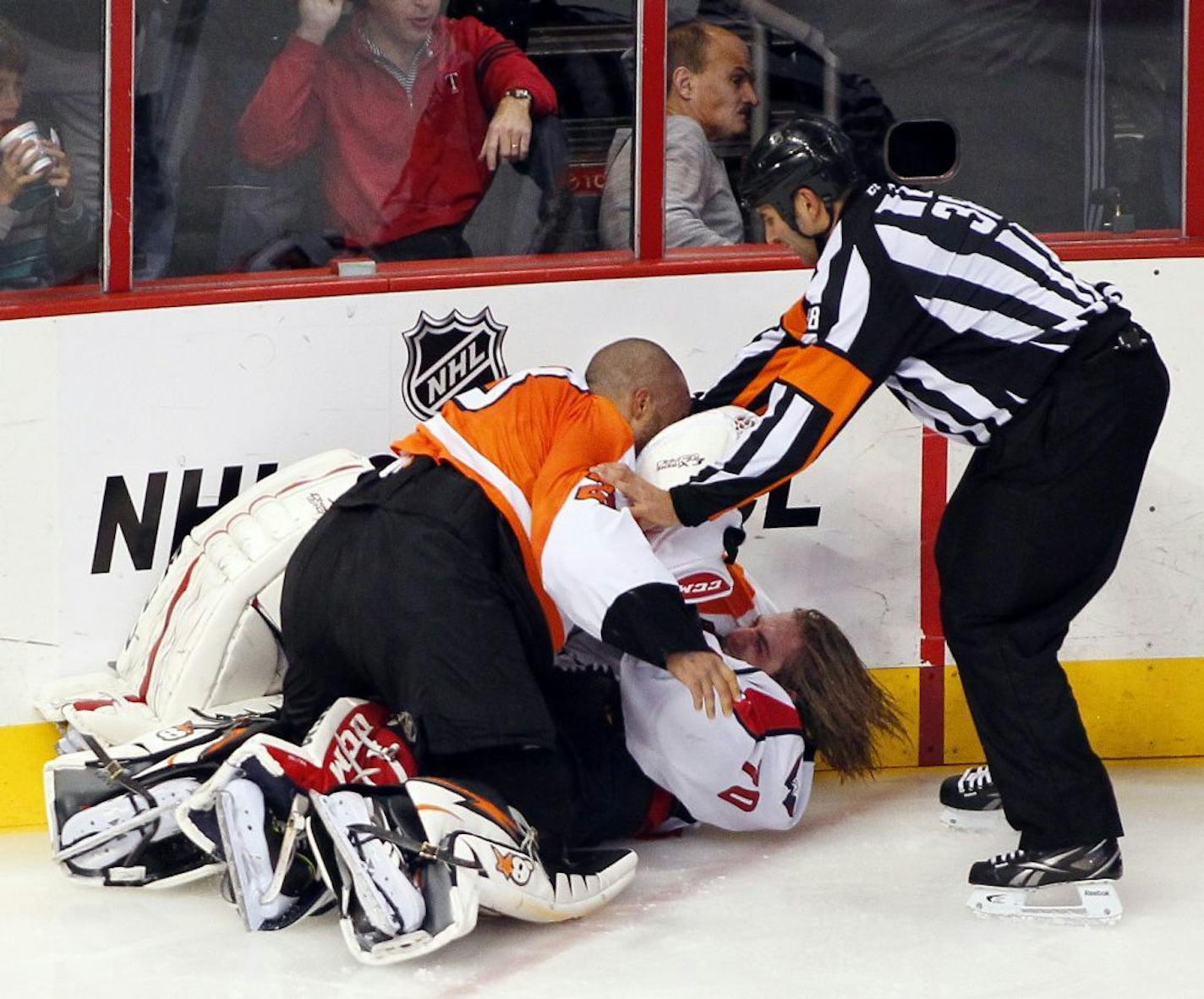 Linesman Francois St. Laurent, right, tries to pull Philadelphia Flyers goalie Ray Emery, top, off of Washington Capitals goalie Braden Holtby during a melee in the third period of an NHL hockey game Friday, Nov. 1, 2013, in Philadelphia. The Capital won 7-0.