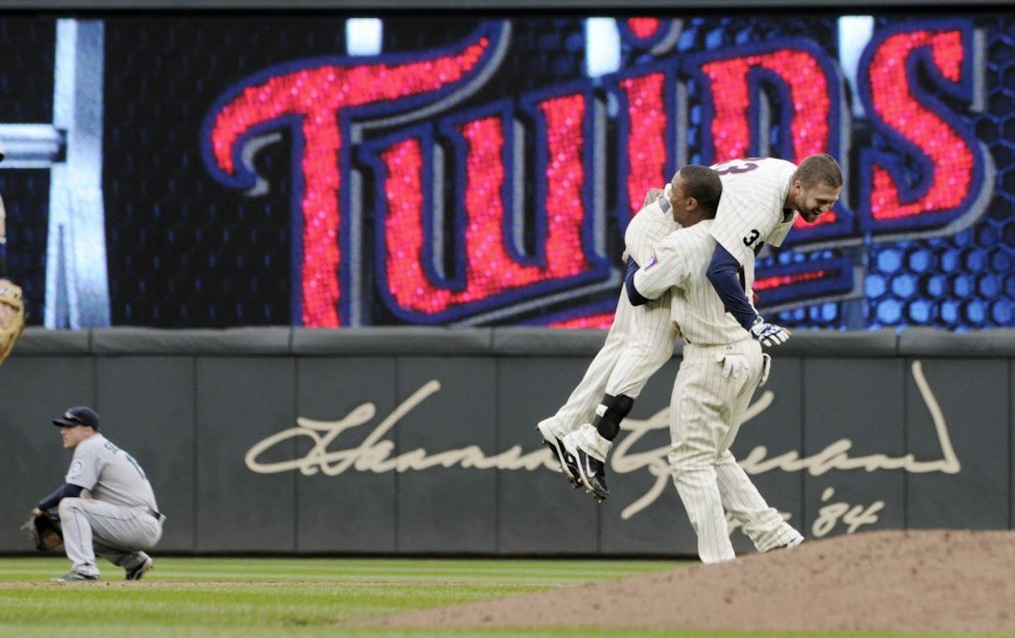 Seattle Mariners shortstop Kyle Seager, left, kneels dejected as Minnesota Twins' Ben Revere gives a congratulatory lift to Rene Rosoni (23) after Tosoni's hit the game-winning RBI double in their 3-2 win in a baseball game Thursday, Sept. 22, 2011 in Minneapolis.