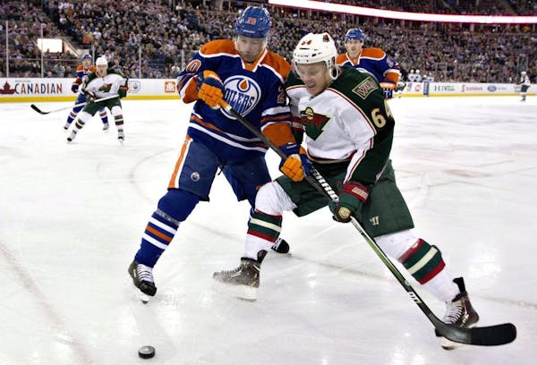 Mikael Granlund and Edmonton Oilers' Eric Belanger scrap for the puck earlier this season.
