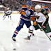 Mikael Granlund and Edmonton Oilers' Eric Belanger scrap for the puck earlier this season.