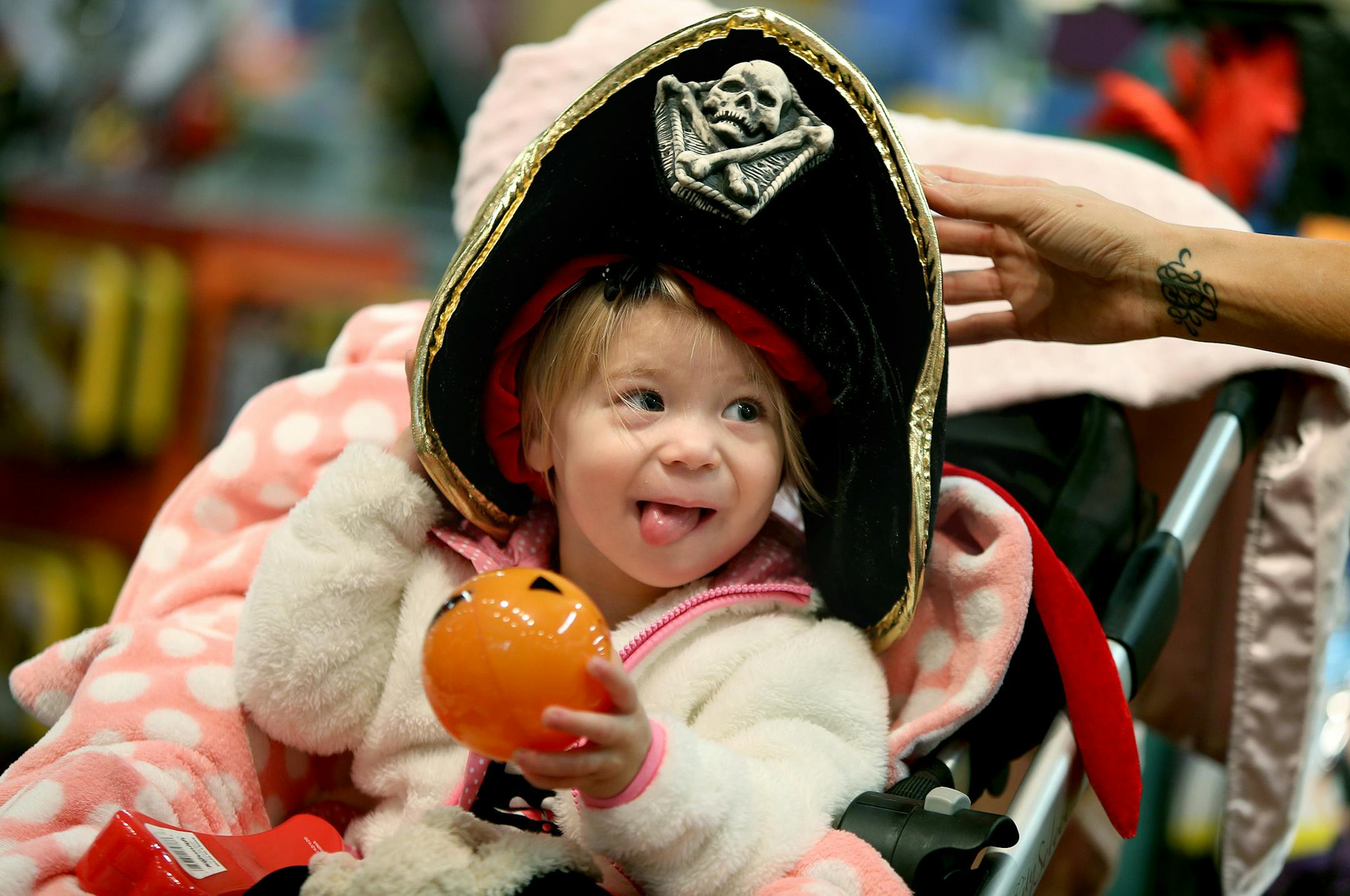 Candice Nelson fitted her daughter Arya Kubesh, 19 months, with a Halloween hat at Creative Kidstuff at Galleria Mall in Edina, MN, Thursday, October 17, 2013. Americans plan to spend $2.6 billion on Halloween this year, mostly on costumes and candy. But the National Retail Federations says consumers are still skittish about spending in an uncertain economy. (ELIZABETH FLORES/STAR TRIBUNE) ELIZABETH FLORES • eflores@startribune.com