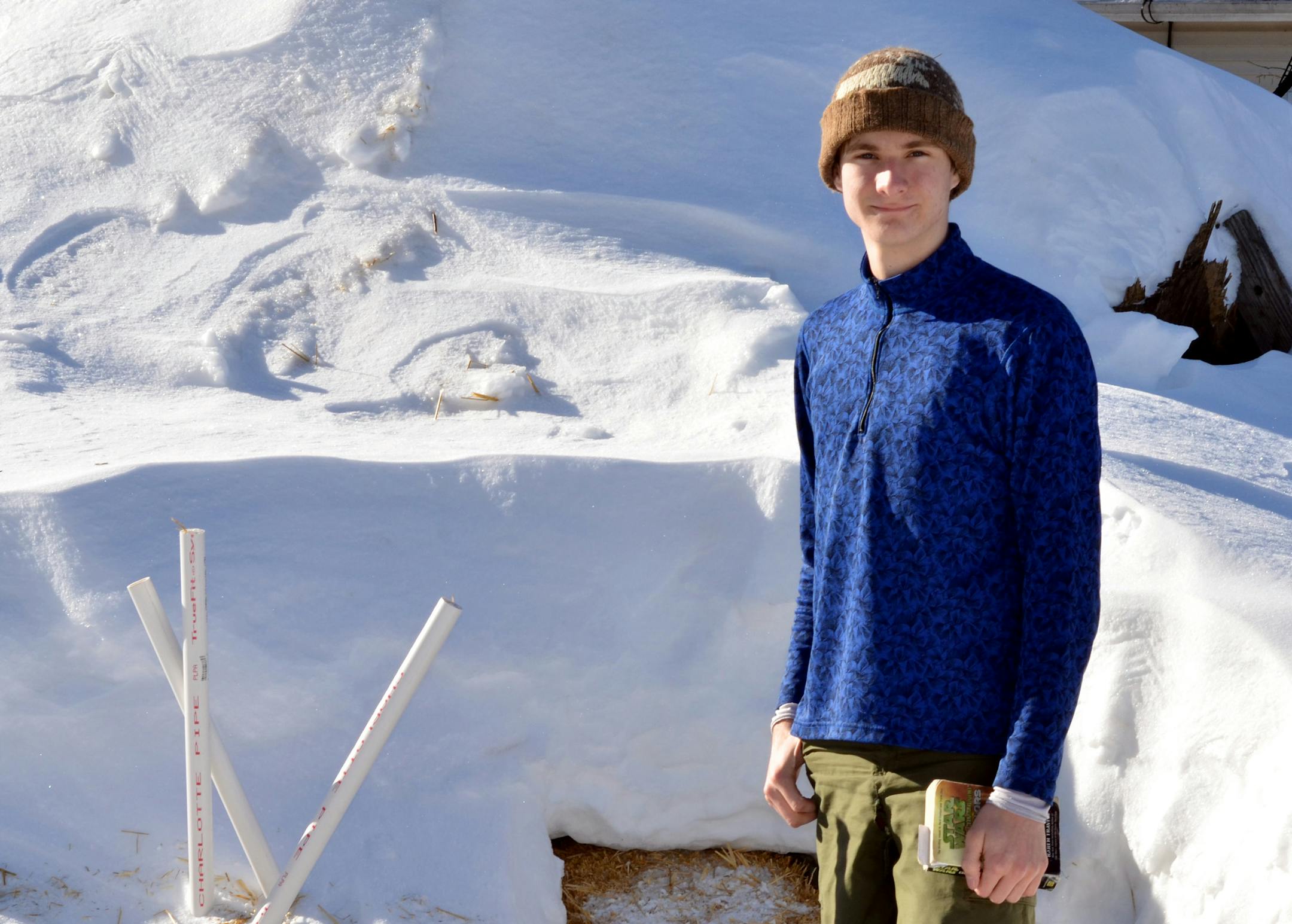 In this Jan. 18, 2014 photo provided by his father Mark Hummel, Rudy Hummel stands in front of his snow cave outside his home in Hermantown, Minn. After spending 365 straight nights outside, enduring 76 subzero nights in his snow cave, Rudy was preparing Friday, June 6, 2014, to spend one last night outside him his yard to complete his quest to spend every night sleeping outside for a full year.