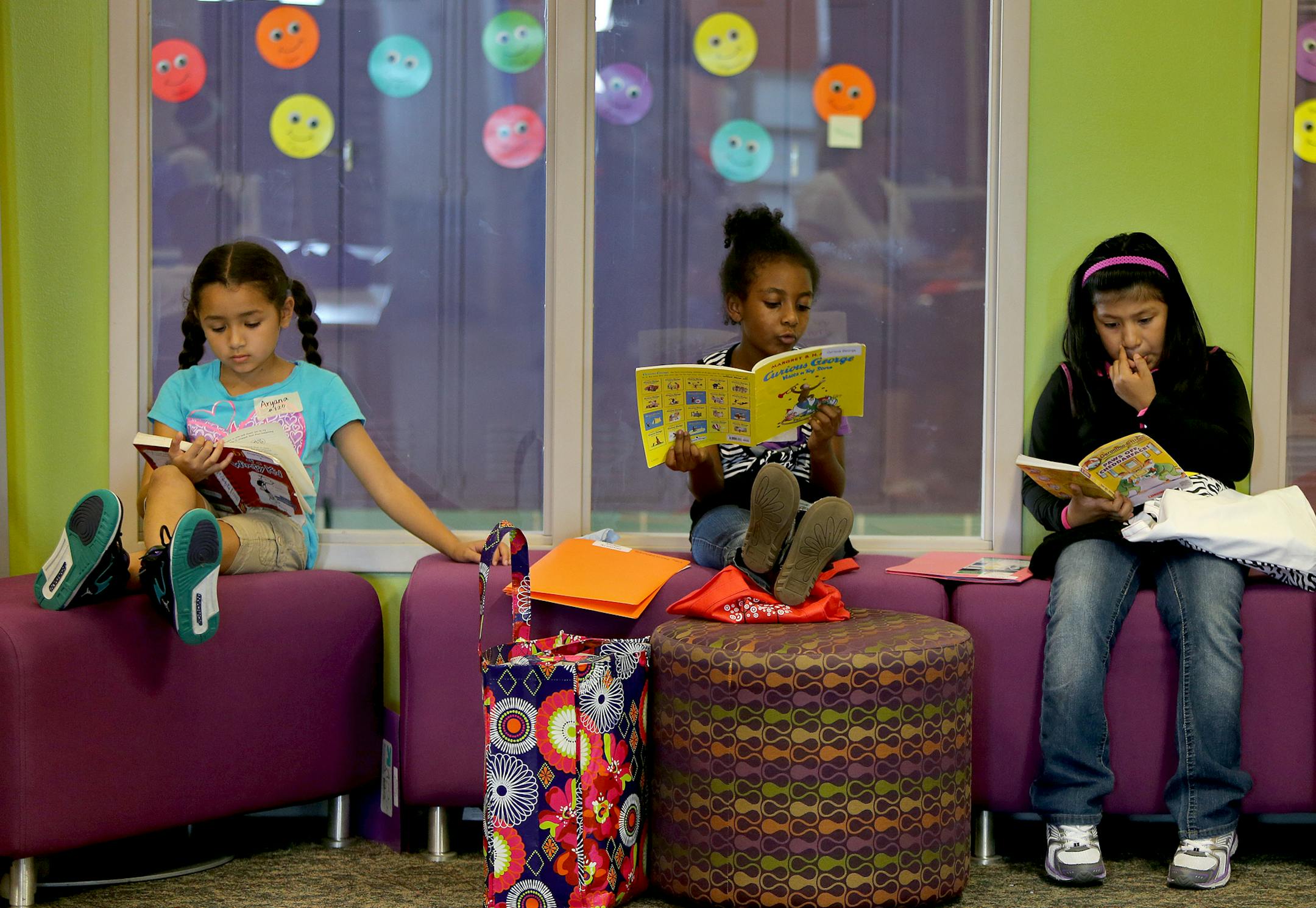 Second-graders Aryana Cole, left, Tenagnework Agedie, center, and Jennifer Balboa, found a spot to read at North Park Elementary School in Fridley, MN, Friday, September 6, 2013. The school's principal Jeff Cacek is now changing the century-old model of how a classroom used to be to a modern era classroom. The design is one large space where there are no desks for any of the students or teachers. It's sparsely furnished with tables and stools and is separated by a glass partition. (ELIZABETH FLO