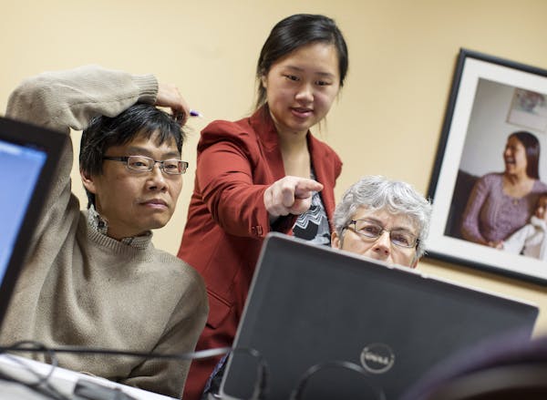 Navigator Nou Chee Lee, center, helps Taichi Chen, left, and Robin Chen of New Hope sign up for MNsure health benefits before the Dec. 23 deadline for