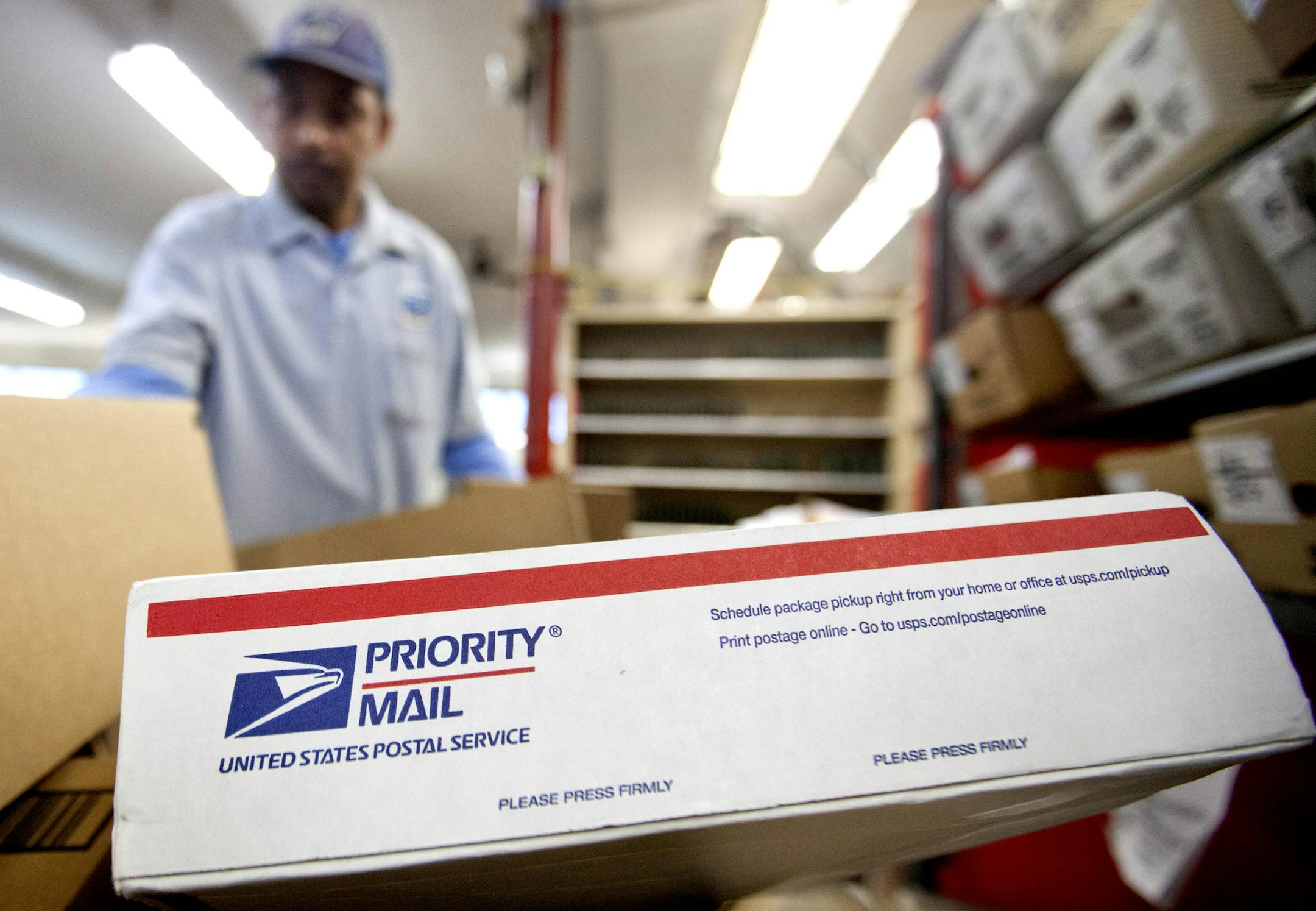 FILE - In this Thursday, Feb. 7, 2013, file photo, packages wait to be sorted in a Post Office as U.S. Postal Service letter carrier Michael McDonald, gathers mail to load into his truck before making his delivery run, in Atlanta.