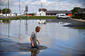 Chad Koosman of Willmar waded through the water Thursday to get an idea of how deep it was in the parking lot behind one of his apartment properties. 