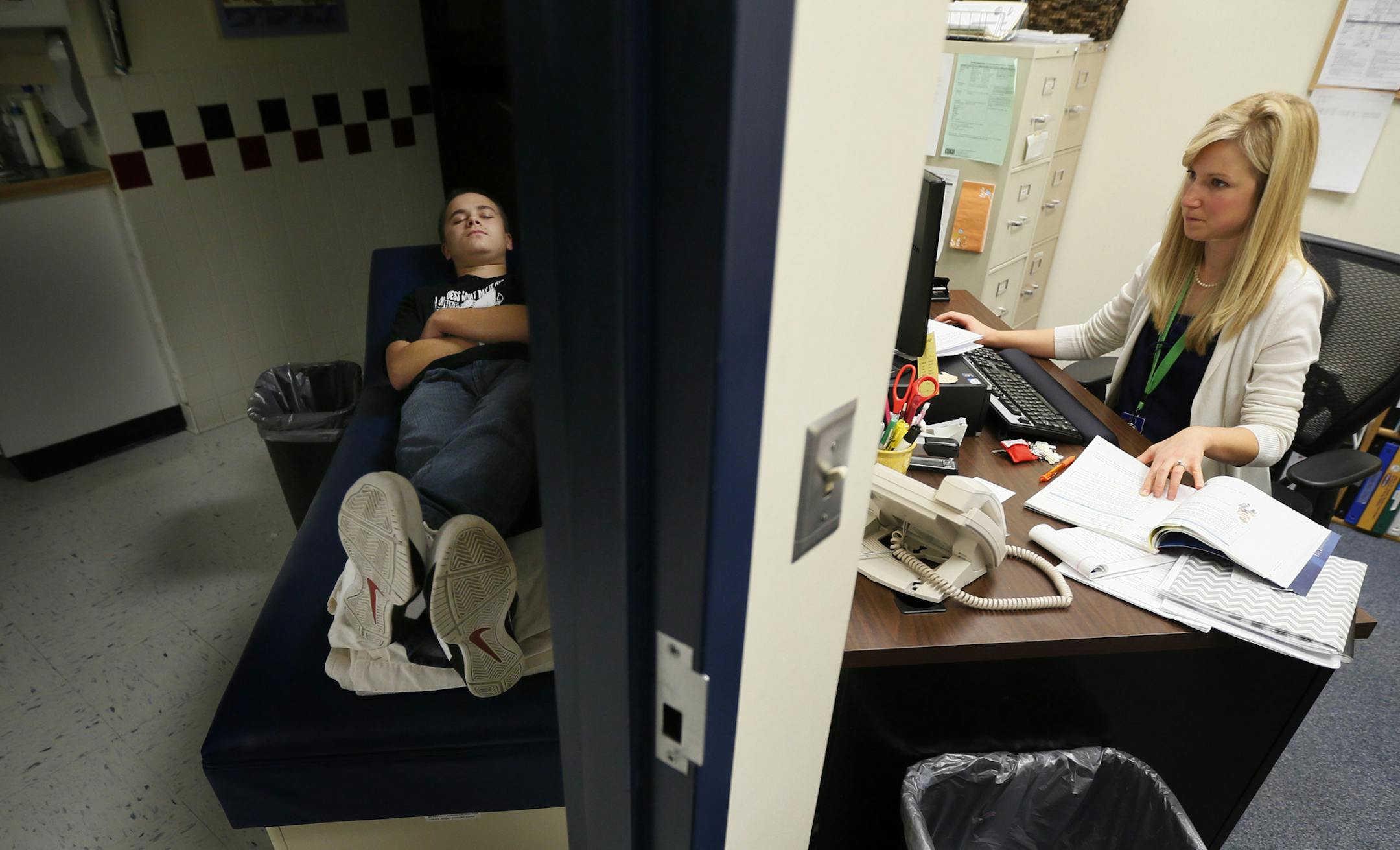 Luke Nelson napped between class as the school nurse Annett Bohnsack worked on the computer . Nelson takes the breaks in a dim room to get a break from bright light Wednesday November 6, 2013 in Dassel , MN. ] JERRY HOLT ‚Ä¢ jerry.holt@startribune.com