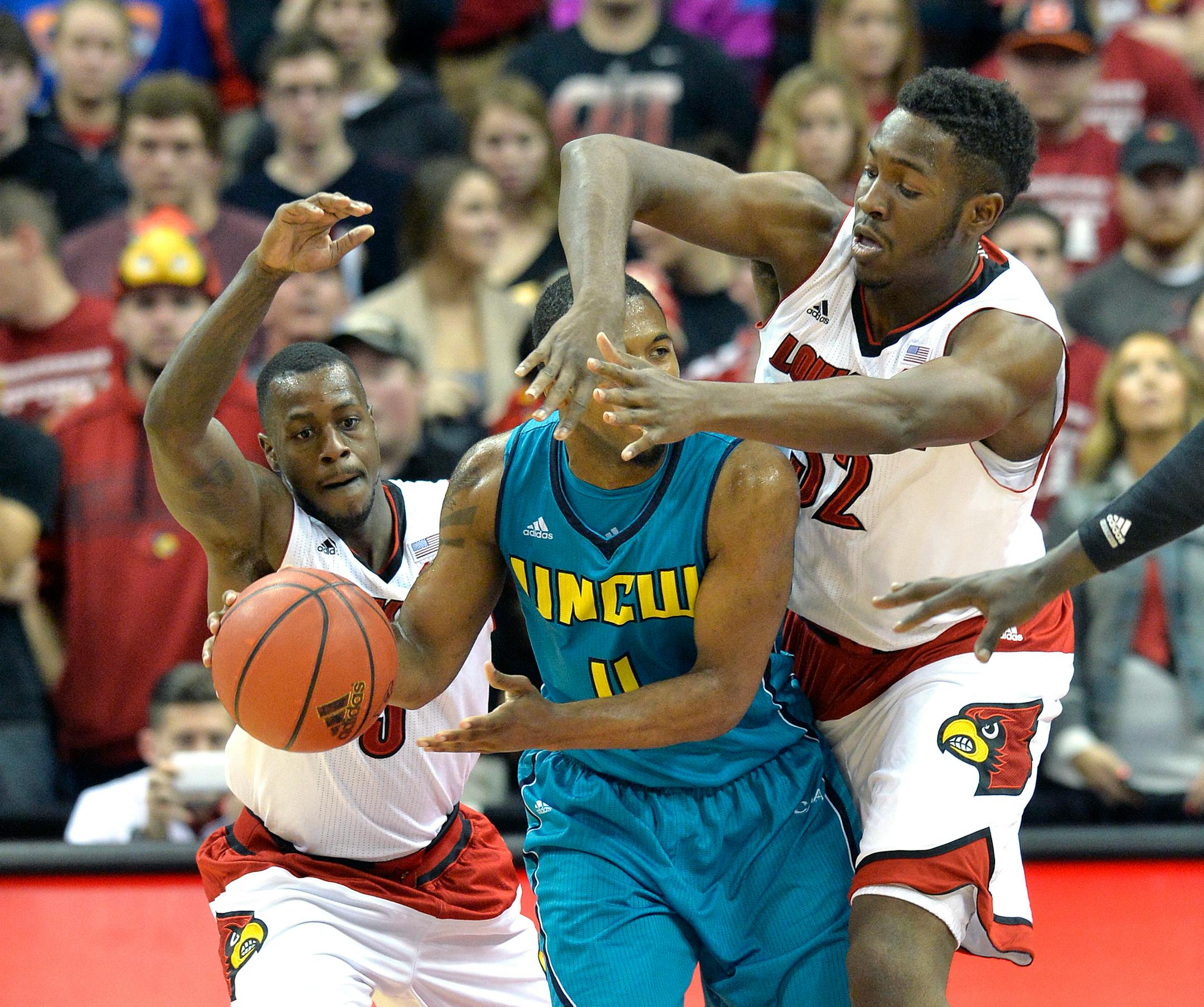 Louisville's Chinanu Onuaku, right, gets his hands in the face of UNC Wilmington's Jordan Talley as Louisville's Chris Jones, left, assists during the second half of an NCAA college basketball game Sunday, Dec. 14, 2014, in Louisville, Ky. Louisville won 68-57. (AP Photo/Timothy D. Easley)