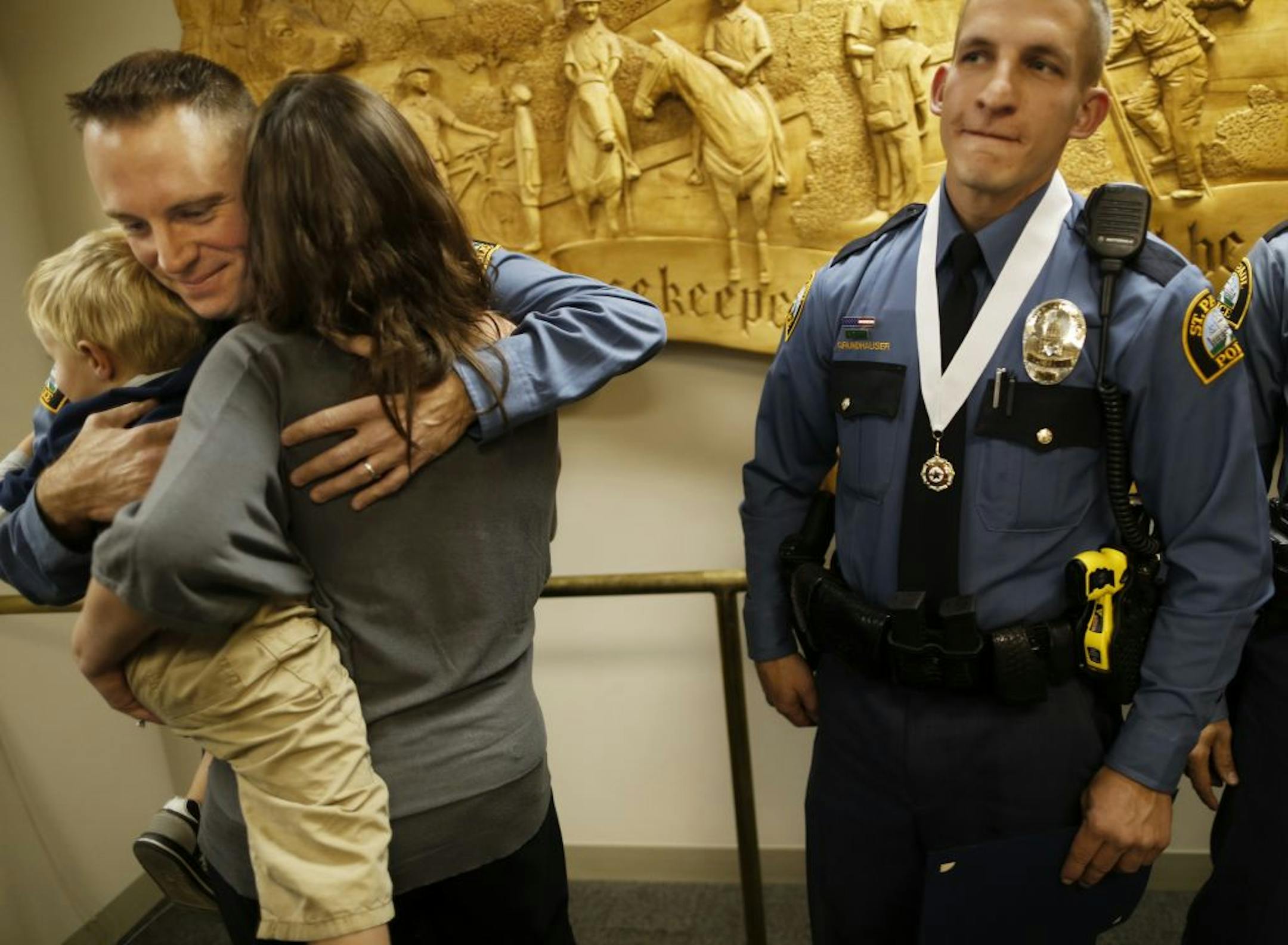St. Paul officer Rod Larson, who helped get people out of a burning house, hugged his family. At right is officer Mark Grundhauser, who calmed a distraught veteran.