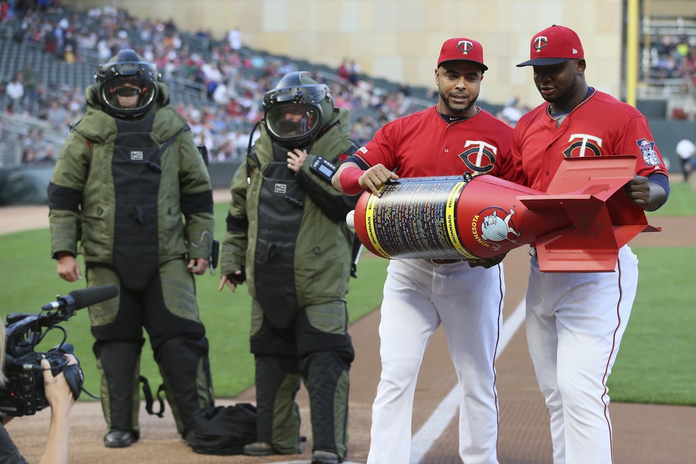 Minnesota Twins' Nelson Cruz, second from right, and Miguel Sano, right, hold the Bomba (Spanish for bomb) award presented to them by members of the Minneapolis Police bomb squad, left, Friday, Sept. 6, 2019, in Minneapolis. The award was presented after the Twins set a single-season record for home runs recently.