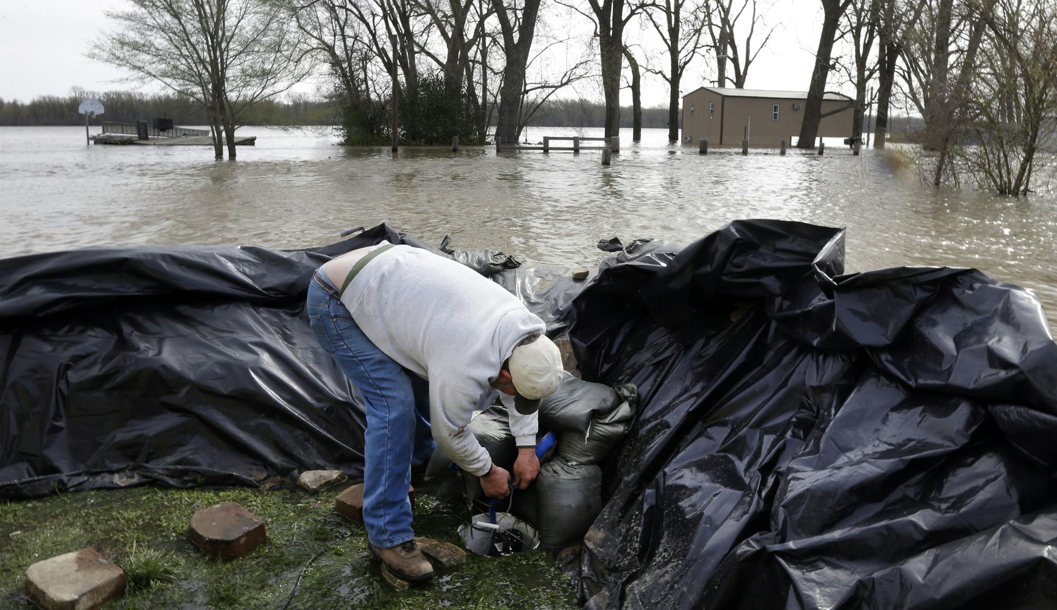 Bob Bailey tinkers with a pump as he tries to keep floodwater from the Mississippi River out of one of his rental properties Sunday, April 21, 2013, in Clarksville, Mo. Many have come to the aid of the tiny community, working since Wednesday to build a makeshift sandbag levee that seemed to be holding as the crest, expected to be 11 feet above flood stage, approaches. (AP Photo/Jeff Roberson)