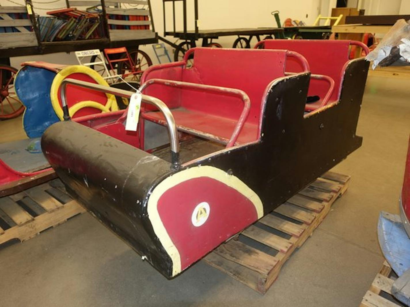 A red-and-black cart with two sets of seats and a safety bar that comes down on each set.