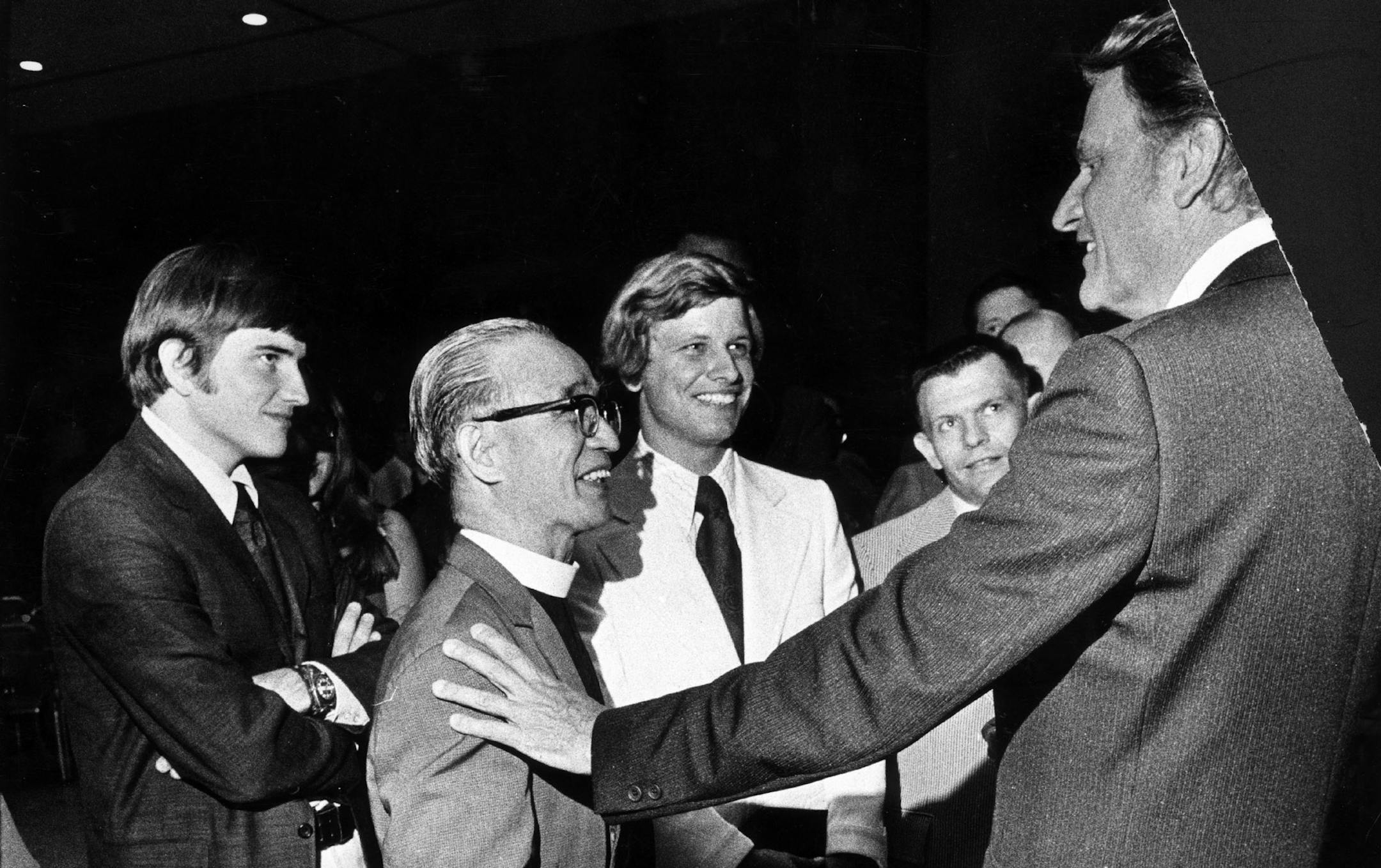 BILLY GRAHAM CRUSADES- MINNESOTA-1973 -- Preacher and evangelist Billy Graham talked with local ministers during a meeting Thursday July 12, 1973. A Graham crusade began the next day at the Minnesota State Fairgrounds in St. Paul. PLEASE NOTE -- The two young men, dark coat far left, and white coat at center, look a lot like Graham's sons -- However, No verification of that on original photo information. Compare to other photos. And look at those noses and cheekbones. Minneapolis Tribune photo b
