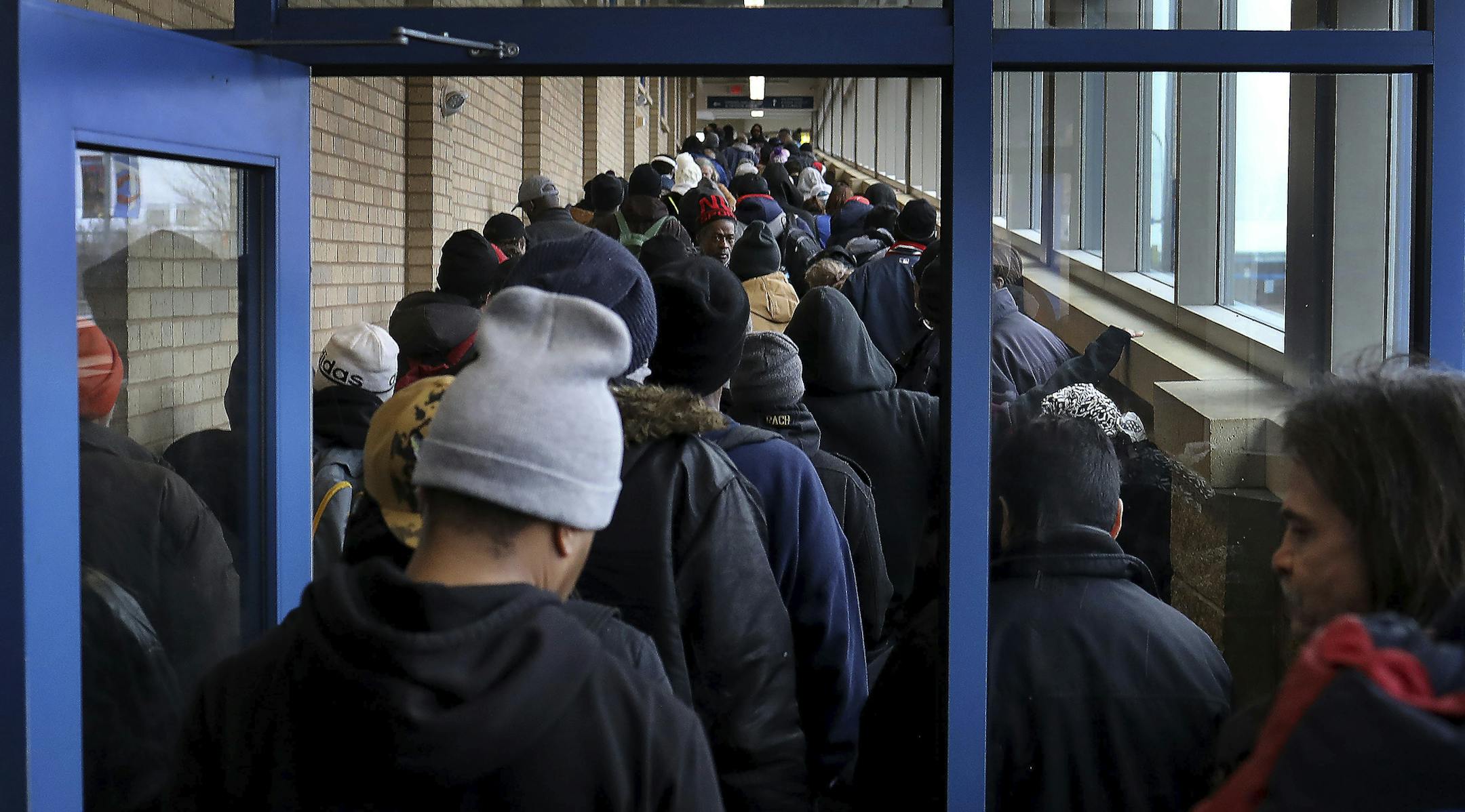 For some social distancing works, for the poor and homeless, getting food to eat doesn't always allow that as evidenced by the line for lunch at Sharing & Caring Hands Tuesday, March 24, 2020, in Minneapolis. People in the line complained of a lack of safe places to go during the day with places like public libraries now closed and also said the lines for services for the homeless appears to be quickly growing. (David Joles/Star Tribune via AP)