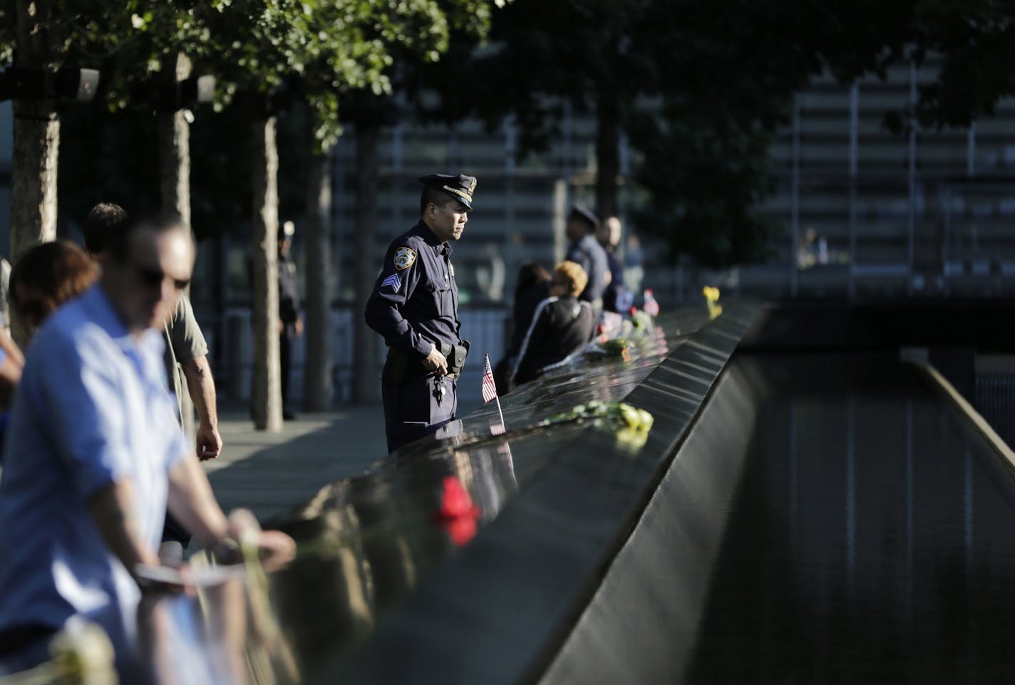 People gather at the side of the north waterfall pool before the ceremony at ground zero in New York, Monday, Sept. 11, 2017. Holding photos and reading names of loved ones lost 16 years ago, 9/11 victims' relatives marked the anniversary of the attacks with a solemn and personal ceremony.