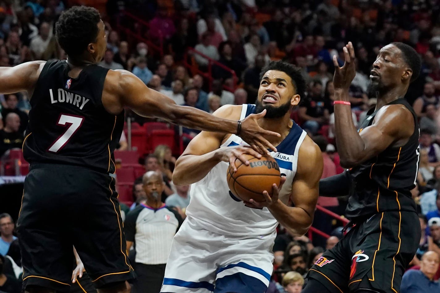 Minnesota Timberwolves center Karl-Anthony Towns (32) drives to the basket as Miami Heat guard Kyle Lowry (7) and center Bam Adebayo (13) defend during the first half of an NBA basketball game, Saturday, March 12, 2022, in Miami. (AP Photo/Marta Lavandier)