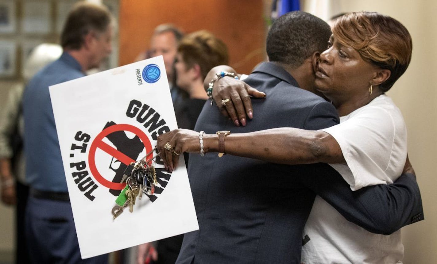 St. Paul Mayor Melvin Carter hugged Dora Jones-Robinson at police headquarters after speaking during a news conference Tuesday in response to the recent killings.